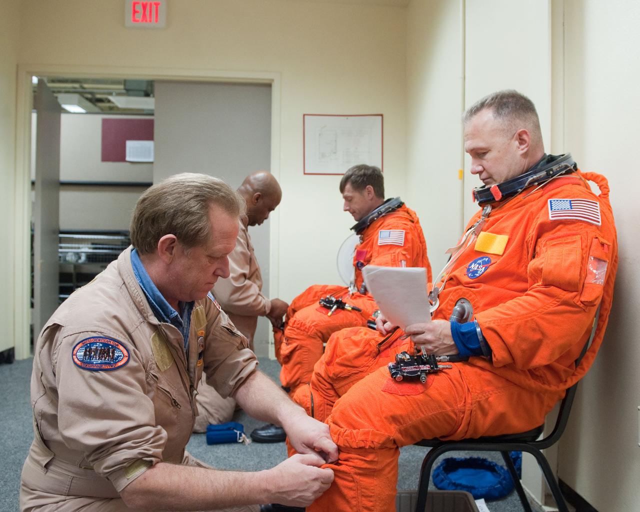 JSC2011-E-023117 (2 March 2011) --- NASA astronauts Doug Hurley (right foreground), STS-135 pilot; and Chris Ferguson, commander, don training versions of their shuttle launch and entry suits in preparation for a training session in the fixed-base shuttle mission simulator (SMS) in the Jake Garn Simulation and Training Facility at NASA's Johnson Space Center. Suit technicians John Hazelhurst (left foreground) and Andre Denard assisted the crew members. Photo credit: NASA or National Aeronautics and Space Administration