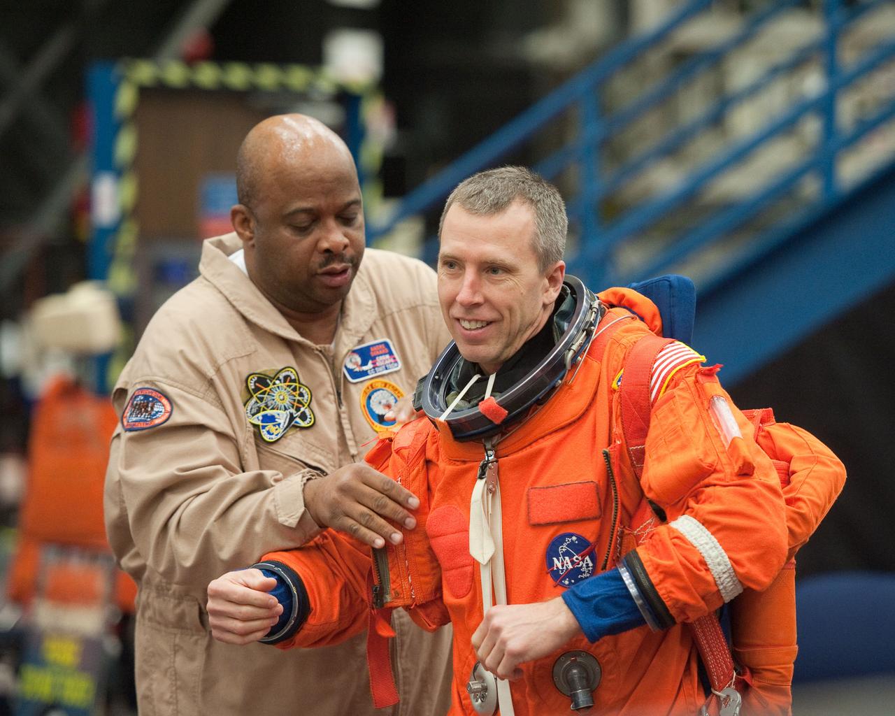JSC2011-E-026919 (11 March 2011) --- NASA astronaut Andrew Feustel, STS-134 mission specialist, dons a training version of his shuttle launch and entry suit in preparation for an ingress/egress training session in a shuttle mock-up in the Space Vehicle Mock-up Facility at NASA's Johnson Space Center. Suit technician Andre Denard assisted Feustel. Photo credit: NASA or National Aeronautics and Space Administration