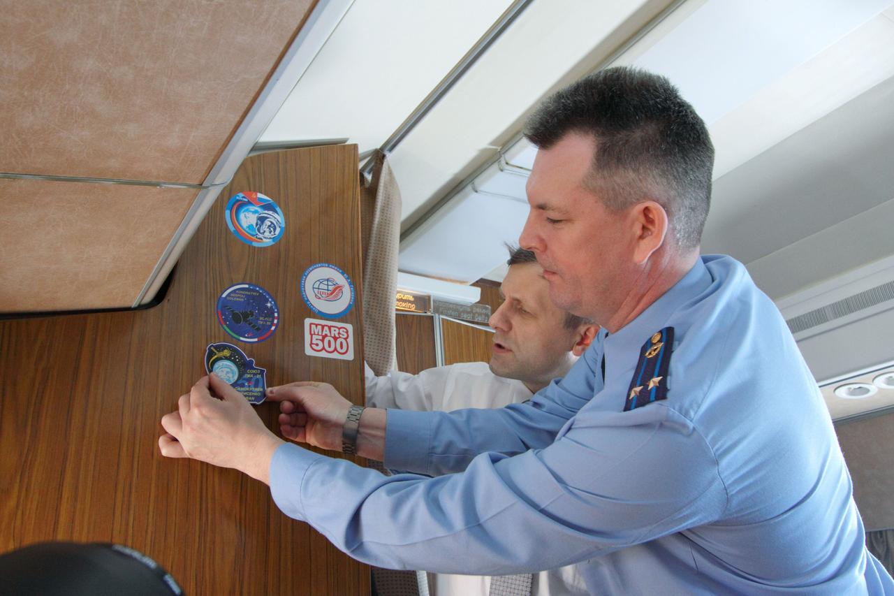 Expedition 27 Soyuz Commander Alexander Samokutyaev (foreground) and Flight Engineer Andrey Borisenko affix their Soyuz crew patch aboard a Gagarin Cosmonaut Training Center plane as they flew from Star City, Russia to the Baikonur Cosmodrome in Kazakhstan March 21, 2011 with their crewmate, NASA Flight Engineer Ron Garan. In Baikonur, they will complete training for their launch April 5 (April 4, U.S. time) on the Soyuz TMA-21 spacecraft to the International Space Station. Credit: NASA/Victor Zelentsov