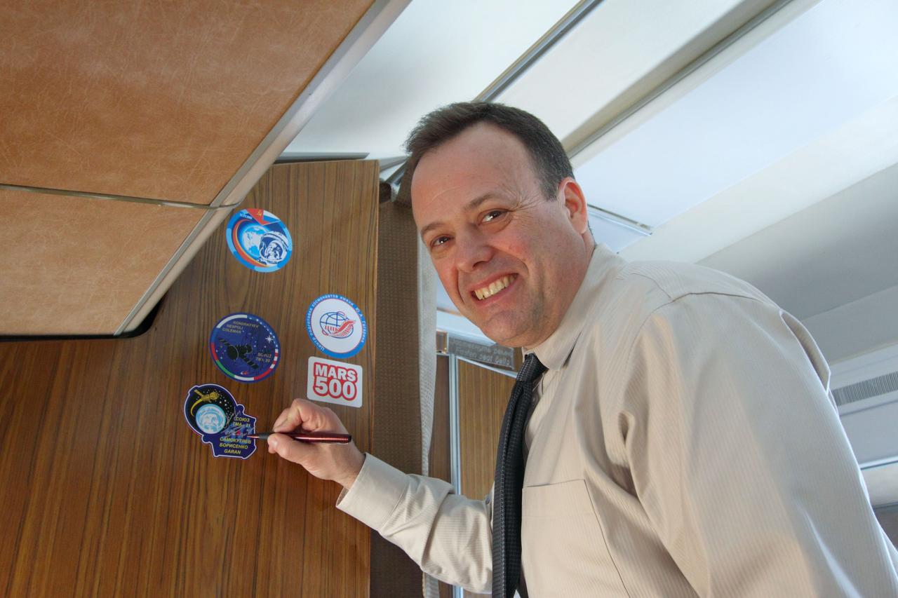 Expedition 27 Flight Engineer Ron Garan of NASA signs his Soyuz crew patch aboard a Gagarin Cosmonaut Training Center plane as he, Flight Engineer Andrey Borisenko and Soyuz Commander Alexander Samokutyaev flew from Star City, Russia to the Baikonur Cosmodrome in Kazakhstan March 21, 2011. In Baikonur, they will complete training for their launch April 5 (April 4, U.S. time) on the Soyuz TMA-21 spacecraft to the International Space Station. Credit: NASA/Victor Zelentsov
