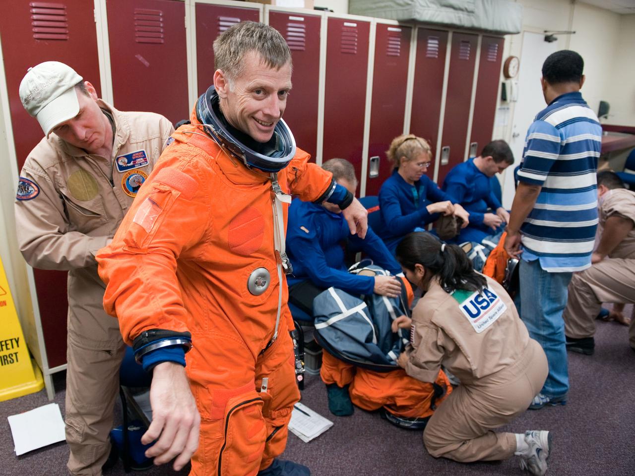 JSC2011-E-028471 (24 March 2011) --- NASA astronaut Chris Ferguson, STS-135 commander, dons a training version of his shuttle launch and entry suit in preparation for a training session in the Full Fuselage Trainer (FFT) in the Space Vehicle Mock-up Facility at NASA's Johnson Space Center. Suit technician Jeremy Spruell assisted Ferguson. Photo credit: NASA or National Aeronautics and Space Administration