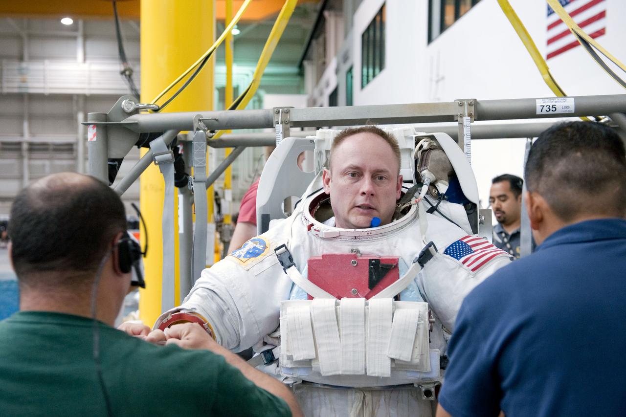 JSC2011-E-029101 (25 March 2011) --- NASA astronaut Michael Fincke, STS-134 mission specialist, gets help donning a training version of his Extravehicular Mobility Unit (EMU) spacesuit in preparation for a spacewalk training session in the waters of the Neutral Buoyancy Laboratory (NBL) at the Sonny Carter Training Facility near NASA's Johnson Space Center. Photo credit: NASA or National Aeronautics and Space Administration