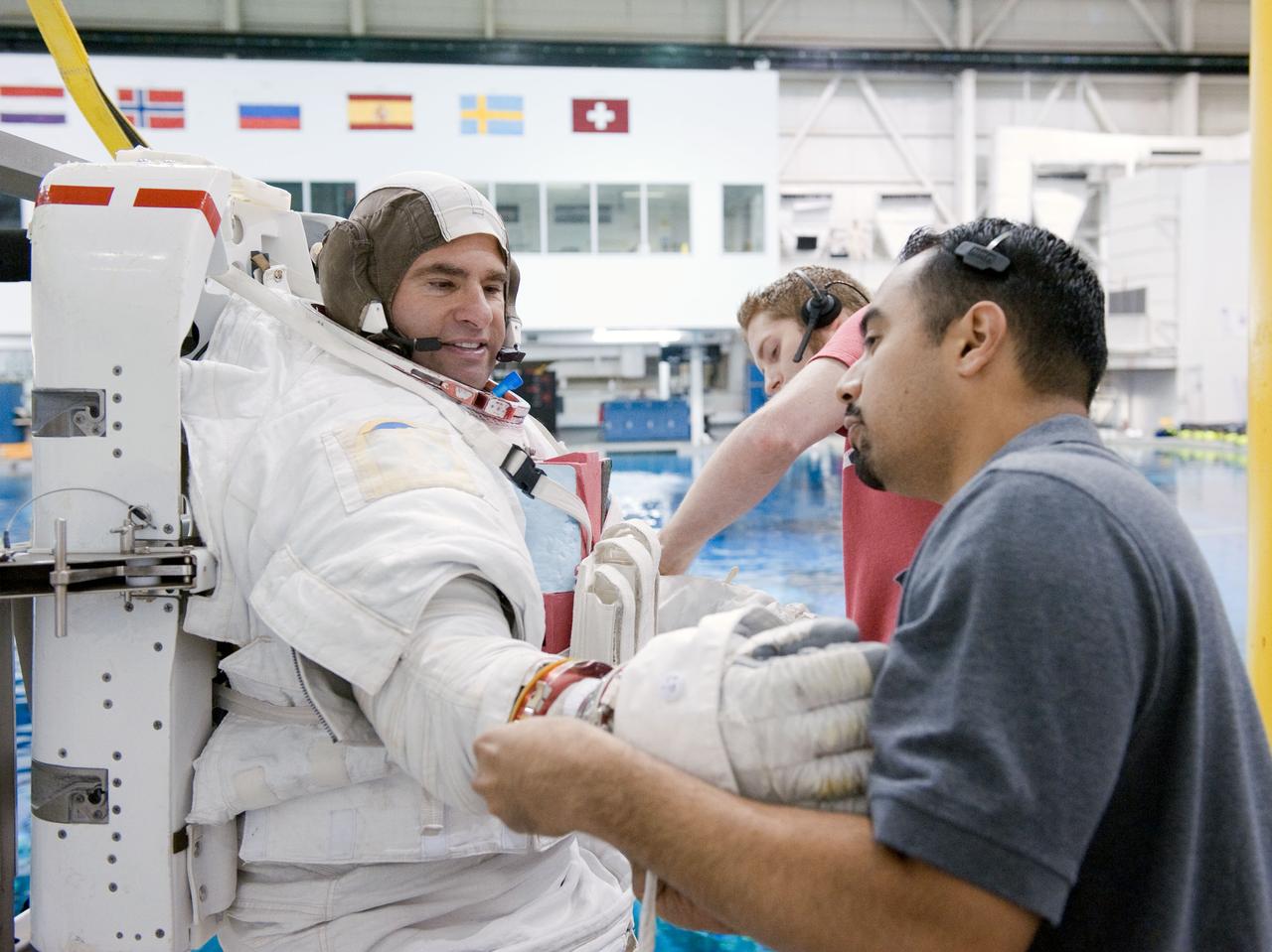 JSC2011-E-029110 (25 March 2011) --- NASA astronaut Greg Chamitoff, STS-134 mission specialist, gets help donning a training version of his Extravehicular Mobility Unit (EMU) spacesuit in preparation for a spacewalk training session in the waters of the Neutral Buoyancy Laboratory (NBL) at the Sonny Carter Training Facility near NASA's Johnson Space Center. Photo credit: NASA or National Aeronautics and Space Administration