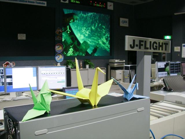 JSC2011-E-029164 (26 March 2011) --- In the HTV mission control room at the Tsukuba Space Center in Japan, some colorful new decoration appeared atop several of the consoles. The origami cranes were distributed in the control rooms in both Houston and Japan. Meantime the Expedition 27 crew onboard the International Space Station joined them in paying tribute to the Japanese population who suffered from the March 11 earthquake and tsunami. Photo credit: Japan Aerospace Exploration Agency (JAXA)