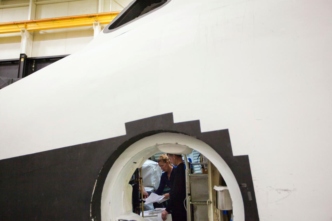 JSC2011-E-040286 (24 March 2011) --- NASA astronauts Sandy Magnus, STS-135 mission specialist, and Chris Ferguson, commander, are seen through a hatch as the crew of STS-135 debriefs after a post-insertion training session in the Full-Fuselage Trainer in the Space Vehicle Mock-up Facility at NASA's Johnson Space Center on March 24, 2011. Photo credit: NASA Photo/Houston Chronicle, Smiley N. Pool