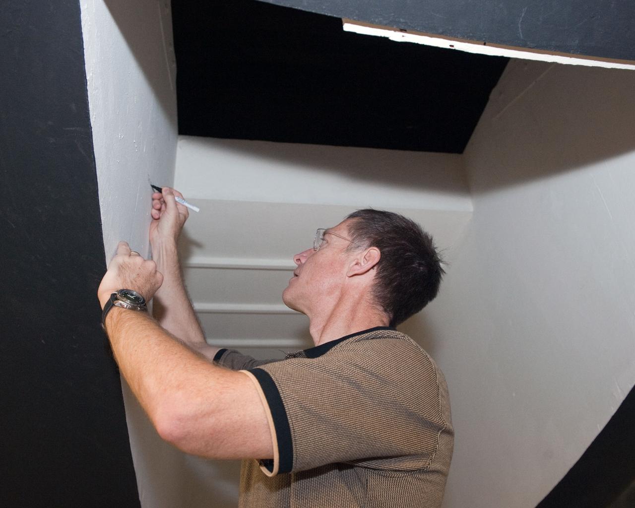 JSC2011-E-043688 (29 April 2011) --- NASA astronaut Chris Ferguson, STS-135 commander, signs his name on hardware during an ingress/egress timeline training session in the Space Vehicle Mock-up Facility at NASA's Johnson Space Center. Photo credit: NASA
