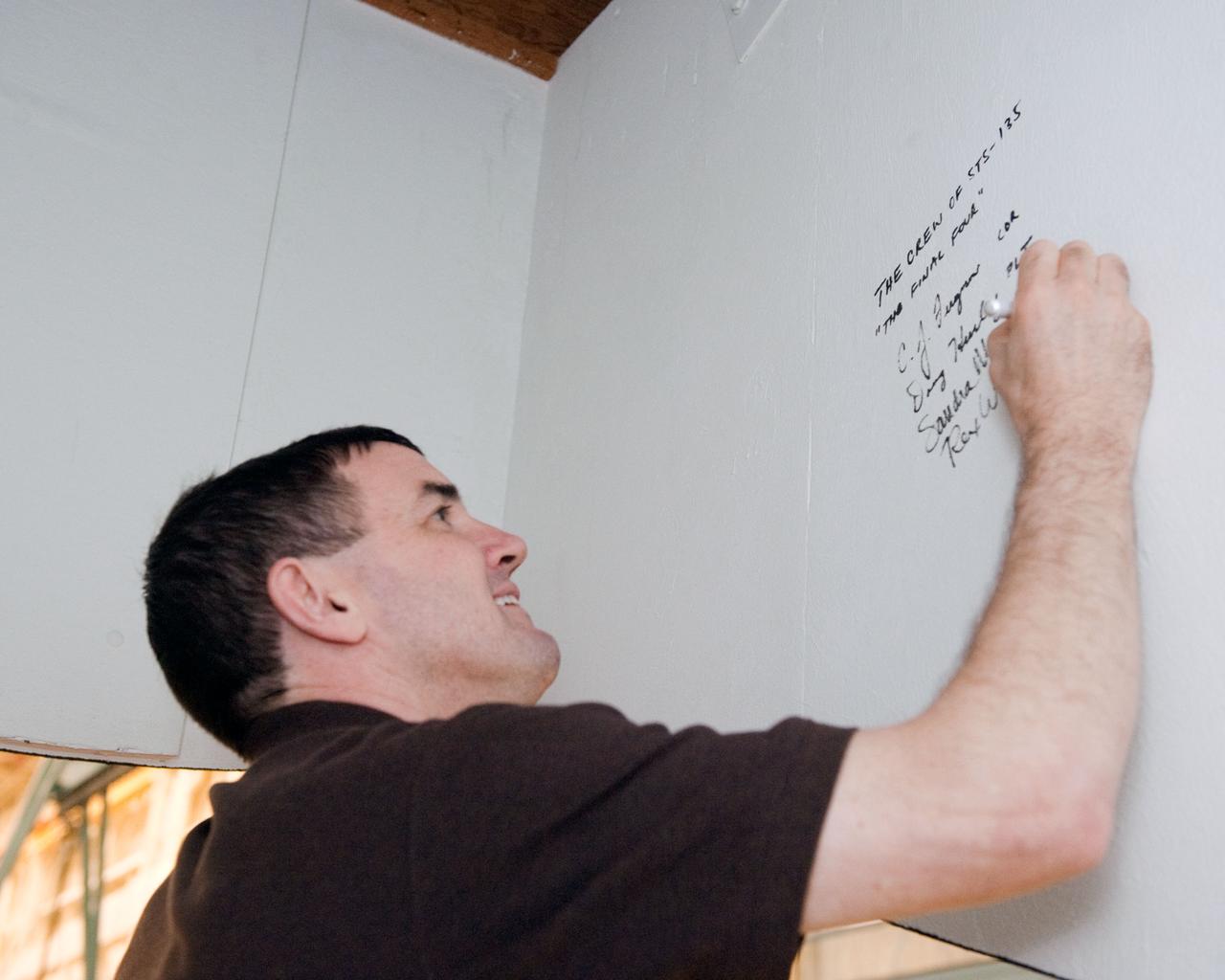 JSC2011-E-043692 (29 April 2011) --- NASA astronaut Rex Walheim, STS-135 mission specialist, signs his name on hardware during an ingress/egress timeline training session in the Space Vehicle Mock-up Facility at NASA's Johnson Space Center. Photo credit: NASA
