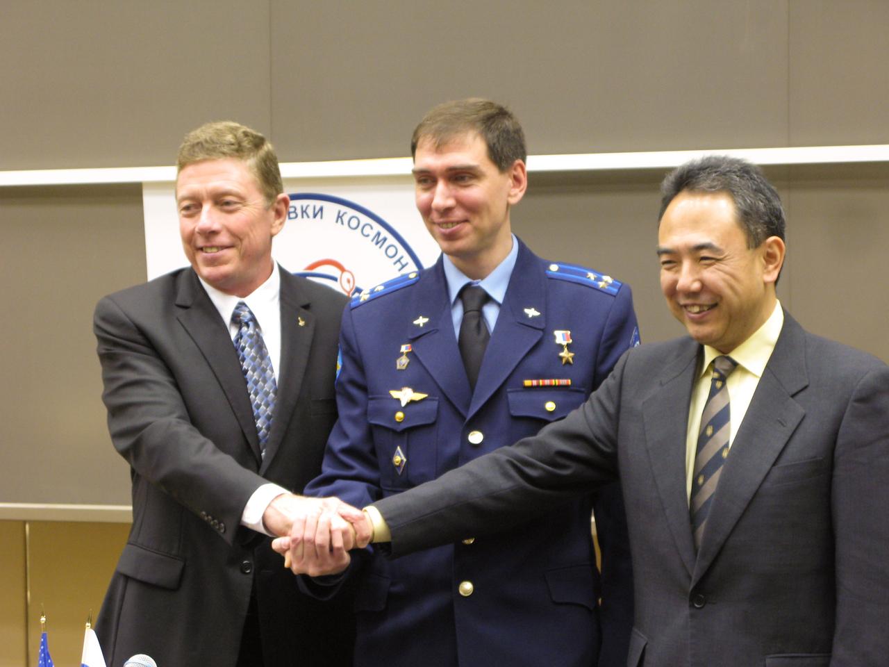 At the Gagarin Cosmonaut Training Center in Star City, Expedition 28 Flight Engineer Mike Fossum of NASA (left), Japan Aerospace Exploration Agency Flight Engineer Satoshi Furukawa (center) and Soyuz Commander Sergei Volkov clasp hands after a news conference May 16, 2011 as they prepare for their launch June 8 in the Soyuz TMA-02M spacecraft from the Baikonur Cosmodrome in Kazakhstan for the International Space Station.