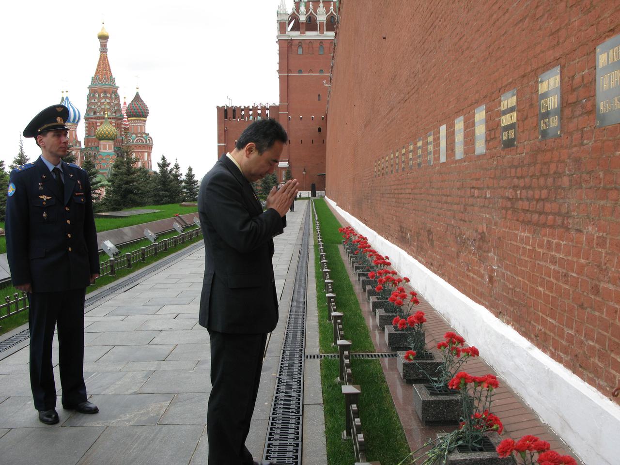 Expedition 28 Flight Engineer Satoshi Furukawa pays his respects to those interred in the Kremlin Wall in Red Square in Moscow May 16, 2011 as he and his crewmates conducted traditional activities in advance of their launch June 8 in the Soyuz TMA-02M spacecraft from the Baikonur Cosmodrome in Kazakhstan for the International Space Station. Looking on is Soyuz Commander Sergei Volkov, who along with Furukawa, will be launched with NASA Flight Engineer Mike Fossum to spend almost six months on the complex.