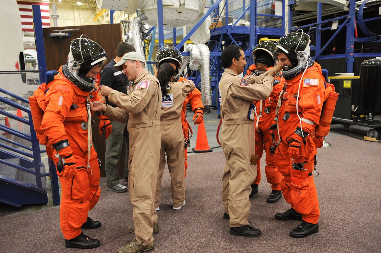 JSC2011-E-050068 (24 May 2011) --- STS-135 crew members get help with the donning of training versions of their shuttle launch and entry suits in preparation for an ingress/egress training session in the Space Vehicle Mock-up Facility at NASA's Johnson Space Center. Crew members pictured from the left are NASA astronauts Chris Ferguson, commander; Doug Hurley, pilot; Sandy Magnus and Rex Walheim, both mission specialists. Suit technicians assisted the crew members. Photo credit: NASA