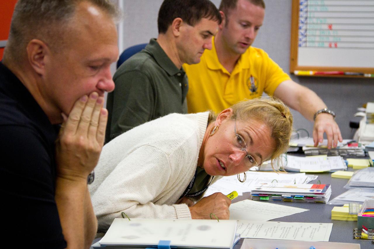 JSC2011-E-059611 (24 June 2011) --- NASA astronaut Sandy Magnus, STS-135 mission specialist, leans out around pilot Doug Hurley, left, to confer with commander Chris Ferguson (out of frame) as the crew of the final space shuttle mission participates in the STS-135 Flight Data File (FDF) review at NASA?s Johnson Space Center June 24, 2011. The review involves examining and annotating more than 200 procedure books and cue cards that comprise all of the detailed technical steps that will be performed during the mission. Photo credit: NASA Photo/Houston Chronicle, Smiley N. Pool