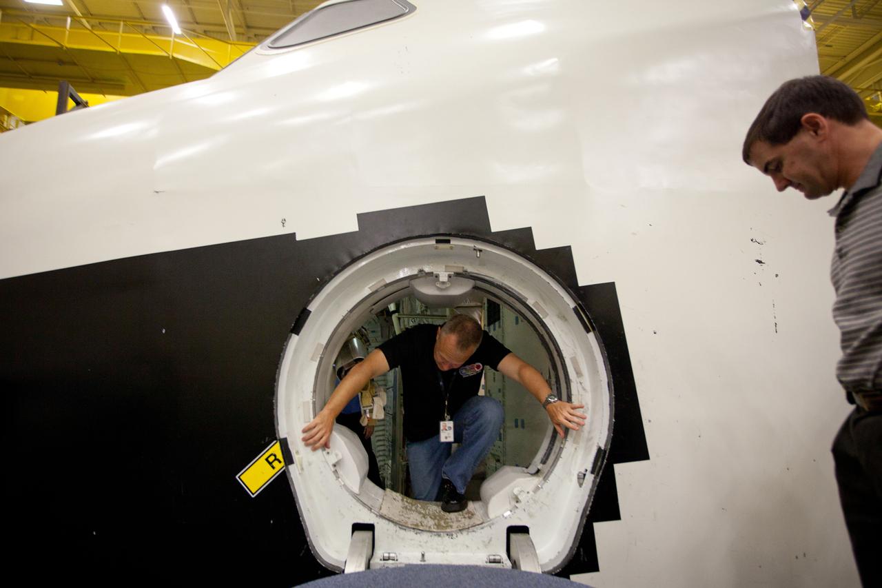 JSC2011-E-060132 (29 June 2011) --- NASA astronaut Doug Hurley crawls out of the Crew Compartment Trainer (CCT-2) mock-up while Rex Walheim waits as the crew of STS-135 trains in the Space Vehicle Mock-up Facility (SVMF) at NASA?s Johnson Space Center June 29, 2011. The training marked the crew's final scheduled session in JSC's Shuttle Vehicle Mock-up Facility. Photo credit: NASA Photo/Houston Chronicle, Smiley N. Pool