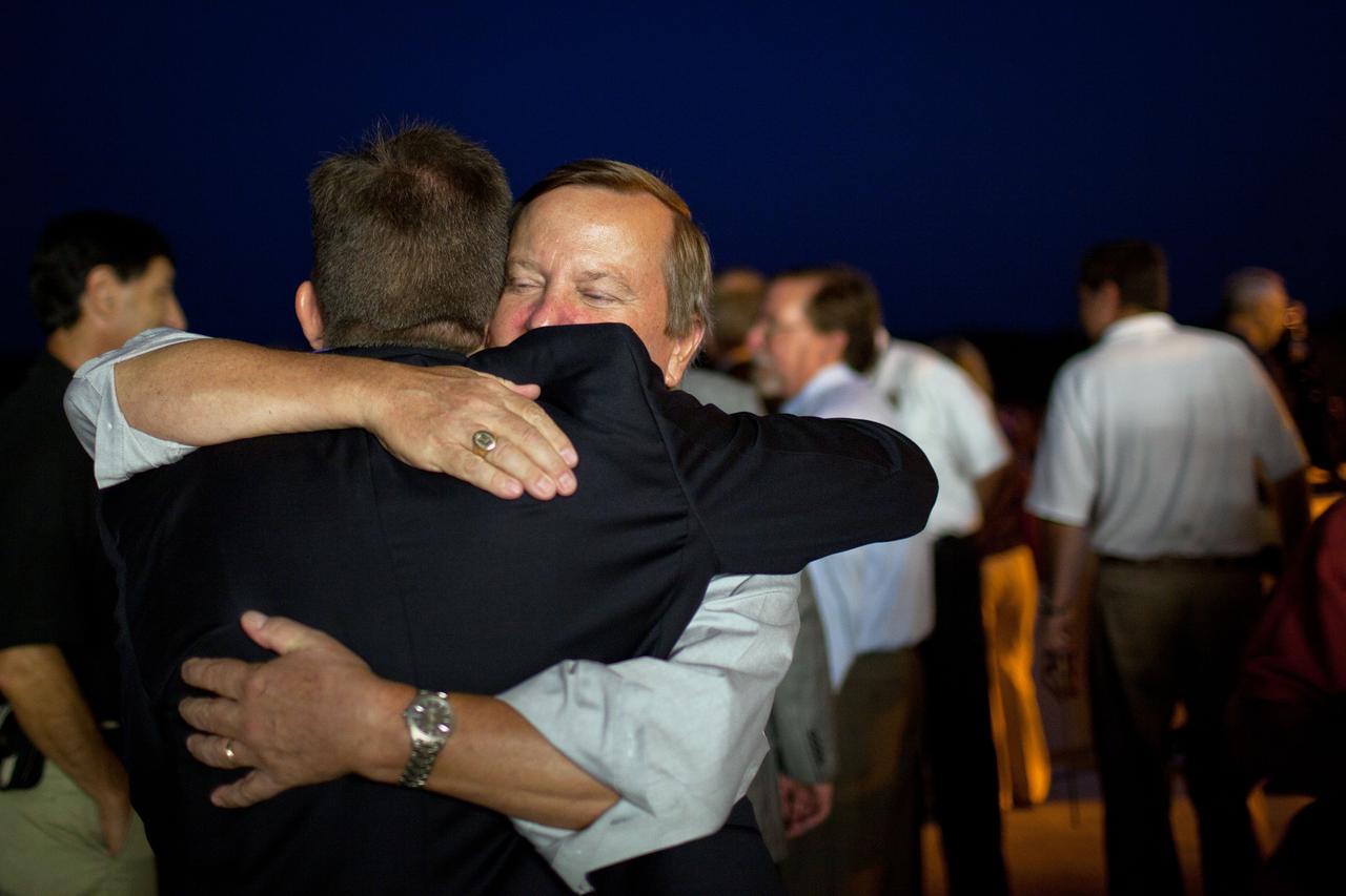 JSC2011-E-067691 (21 July 2011) --- Shuttle launch director Mike Leinbach, facing camera, hugs LeRoy Cain, deputy space shuttle program manager, after the space shuttle Atlantis landed on July 21 at the Kennedy Space Center in Florida. The landing completed STS-135, the final mission of the Space Shuttle Program.  Photo credit: NASA/Houston Chronicle, Smiley N. Pool