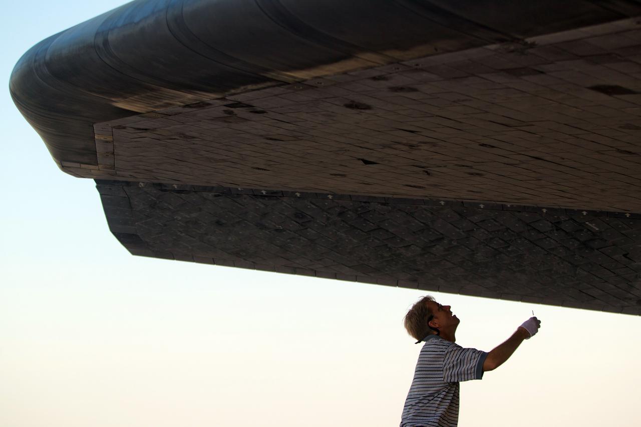 JSC2011-E-068015 (21 July 2011) --- A technician works to secure the space shuttle Atlantis following its landing at the Kennedy Space Center in Florida on July 21, 2011. The landing brought to completion STS-135, the final mission of the NASA Space Shuttle Program. Photo credit: NASA Photo/Houston Chronicle, Smiley N. Pool