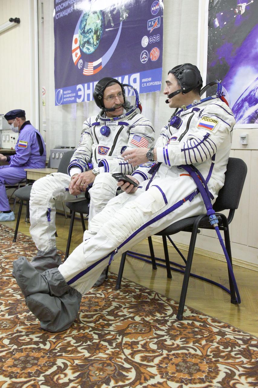 At the Integration Facility at the Baikonur Cosmodrome in Kazakhstan, Expedition 30 Commander Dan Burbank of NASA (left) and Flight Engineer Anatoly Ivanishin share a moment during the checkout of their Russian Sokol launch and entry suits while conducting the first of two “fit checks” of their Soyuz TMA-22 spacecraft. Burbank, Ivanishin and Soyuz Commander Anton Shkaplerov will launch November 14 from Baikonur to the International Space Station.  November 1, 2011  Credit: NASA/Victor Zelentsov 