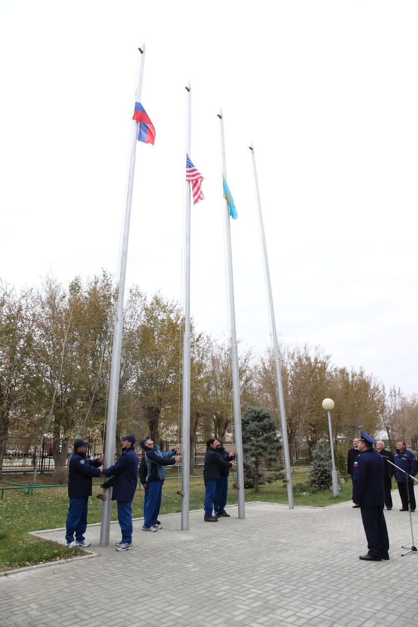 With officials looking on, the Expedition 30 prime and backup crews conducted the traditional flag-raising ceremony outside their Cosmonaut Hotel crew quarter in Baikonur, Kazakhstan on November 2, 2011 as they prepare for the launch of the Soyuz TMA-22 spacecraft on November 14. On the left, prime Soyuz Commander Anton Shkaplerov and Flight Engineer Anatoly Ivanishin hoist the flag of the Russian Federation; in the center, Expedition 30 Commander Dan Burbank of NASA and his backup, NASA’s Joe Acaba (hidden) raise the U.S. flag; on the right, backup crewmembers Sergei Revin and Gennady Padalka raise the flag of Kazakhstan.  Credit: NASA/Victor Zelentsov 