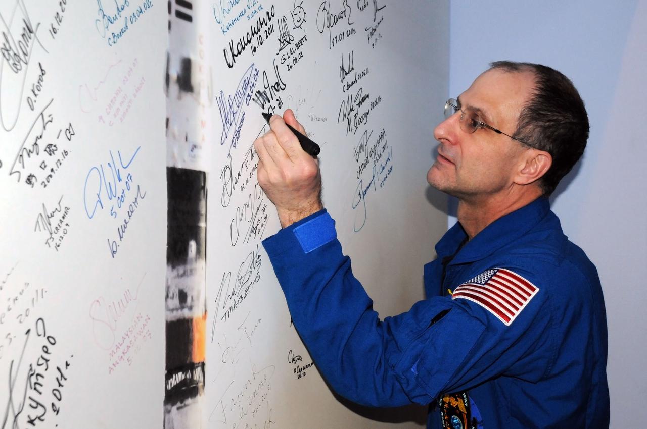 At the Korolev Museum in the Baikonur Cosmodrome in Kazakhstan, Expedition 30 Flight Engineer Don Pettit of NASA signs a picture of a Soyuz rocket December 16, 2011 as he and his Expedition 30 crewmates enter the final days of preparations for launch December 21 on their Soyuz TMA-03M spacecraft. Pettit, Soyuz Commander Oleg Kononenko and Flight Engineer Andre Kuipers of the European Space Agency will spend five and a half months on the station.  Credit: NASA 