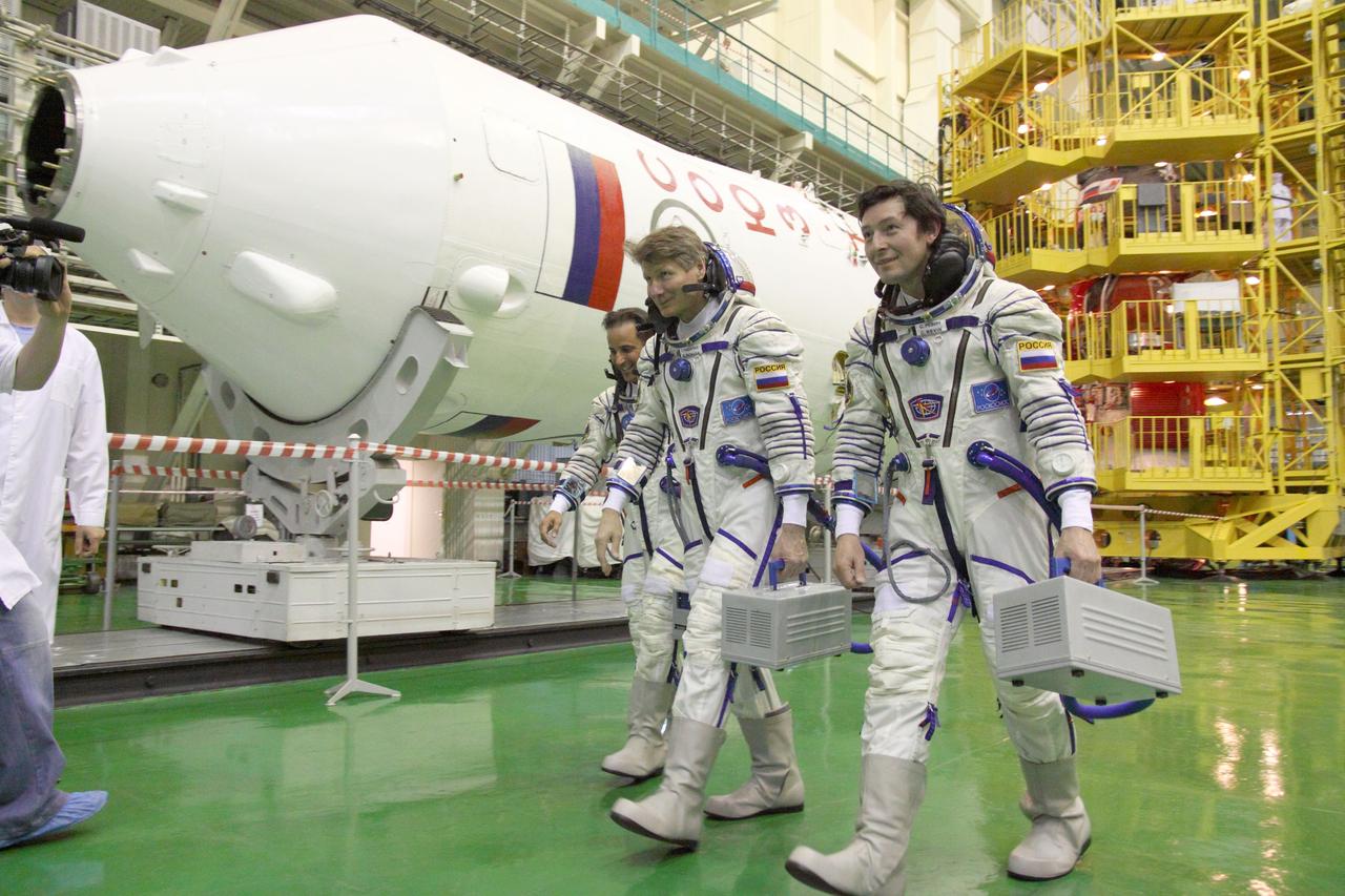 At the Baikonur Cosmodrome in Kazakhstan, Expedition 31/32 Flight Engineer Joe Acaba of NASA (left), Soyuz Commander Gennady Padalka (center) and Flight Engineer Sergei Revin walk past their Soyuz booster rocket in the Cosmodrome’s integration facility May 3, 2012 following a suited “fit check” dress rehearsal of launch day activities in advance of their launch May 15 to the International Space Station. Acaba, Padalka and Revin will spend four months aboard the orbital outpost.  NASA/Victor Zelentsov 