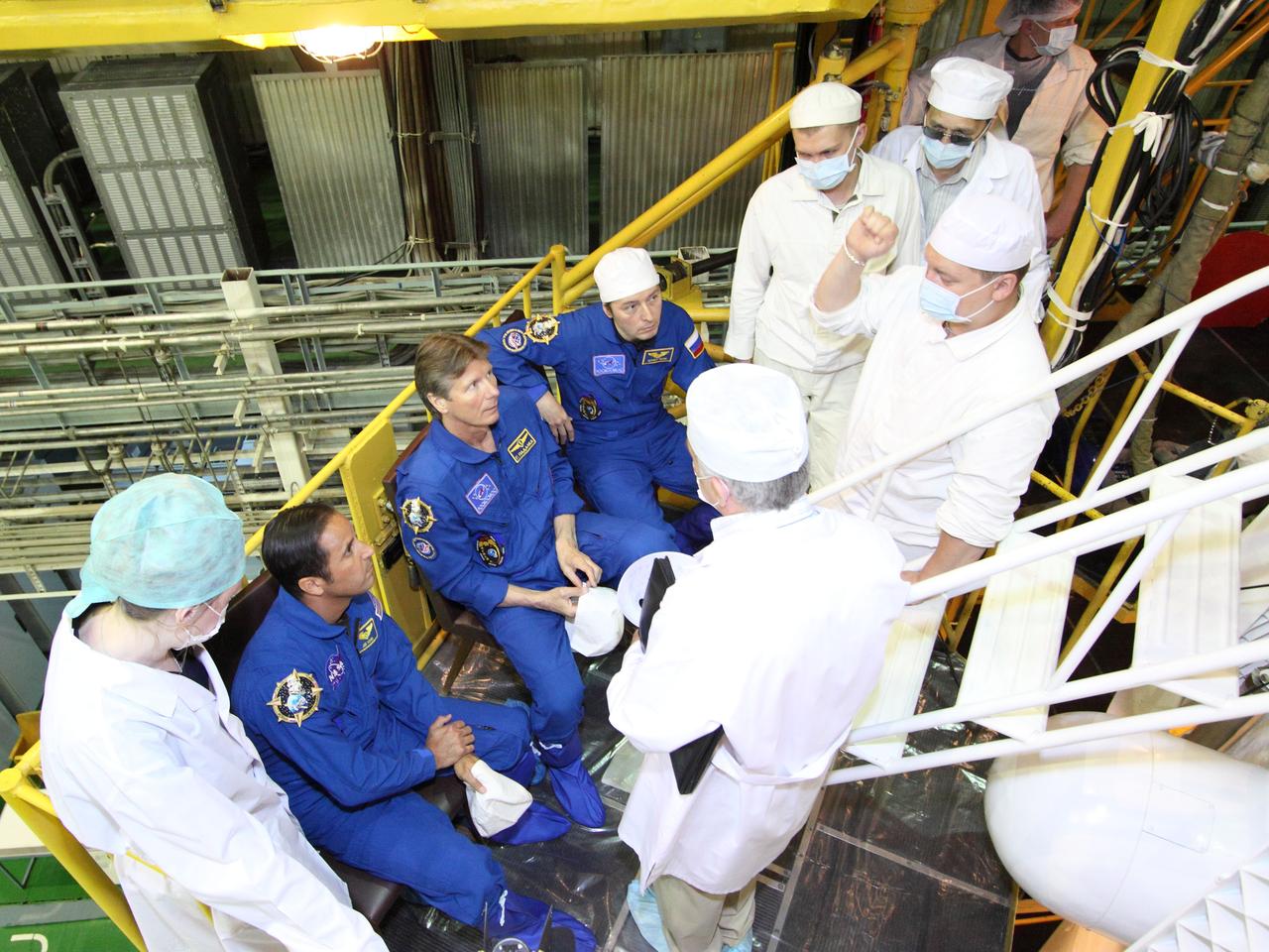 At the Baikonur Cosmodrome in Kazakhstan, the next trio of crewmembers bound for the International Space Station receive a briefing from engineers in front of their Soyuz TMA-04M spacecraft May 11, 2012 as they completed their final “fit check” inspection of the vehicle in its assembly building prior to launch. Expedition 31/32 Flight Engineer Joe Acaba of NASA (left),  Soyuz Commander Gennady Padalka (center) and Flight Engineer Sergei Revin (right) will liftoff from Baikonur May 15 to begin a four-month mission on the orbital complex.  NASA/Victor Zelentsov 