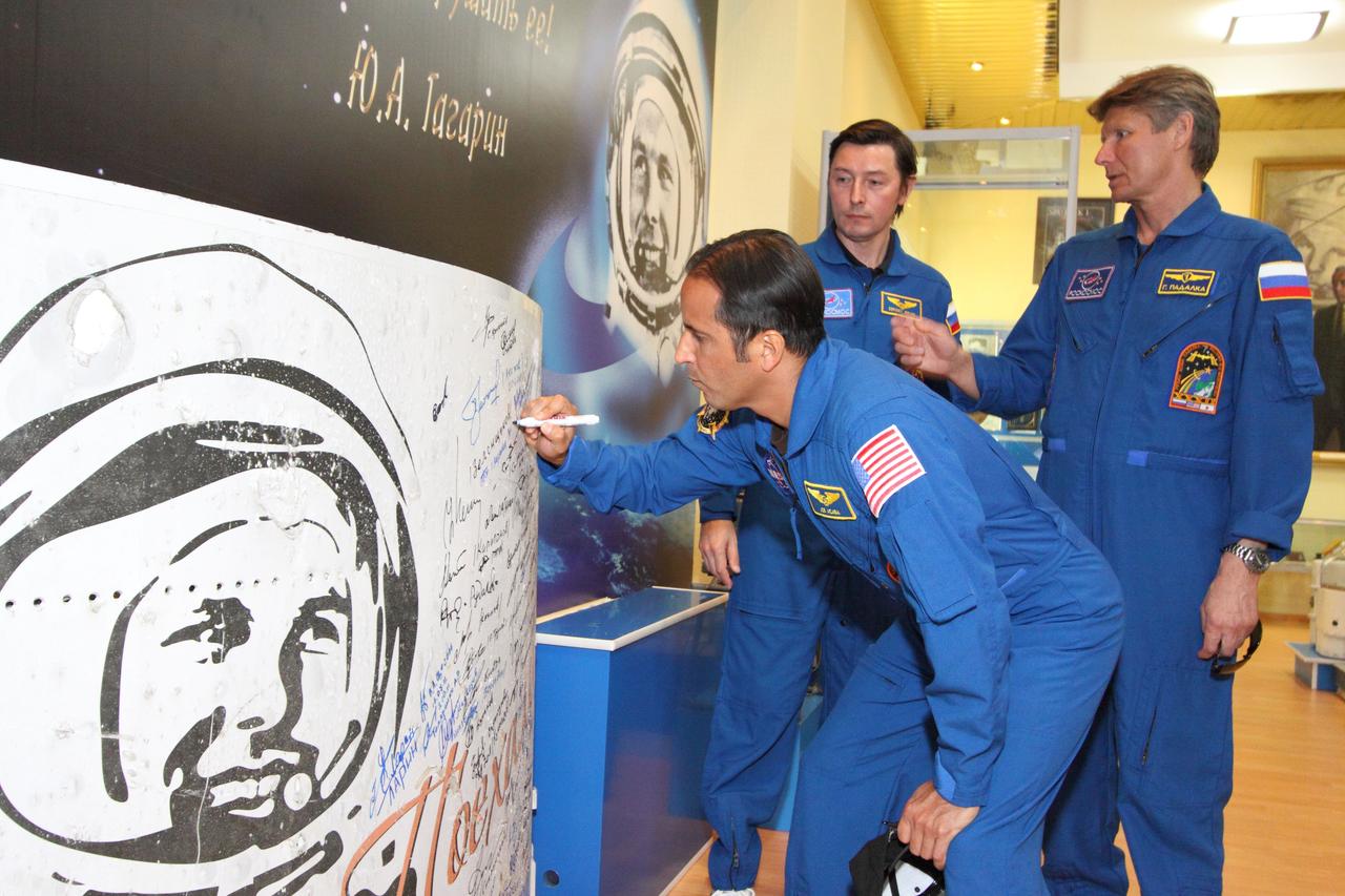 At the historic museum near the launch pad at the Baikonur Cosmodrome in Kazakhstan, Expedition 31/32 Flight Engineer Joe Acaba of NASA signs a mural depicting the likeness of Yuri Gagarin, the first human in space May 11, 2012 as his crewmates, Flight Engineer Sergei Revin (center) and Soyuz Commander Gennady Padalka (right) look on. The trio will launch on their Soyuz TMA-04M spacecraft May 15 from the same launch pad Gagarin left the planet 51 years ago to begin a four-month mission on the International Space Station.  NASA/Victor Zelentsov 
