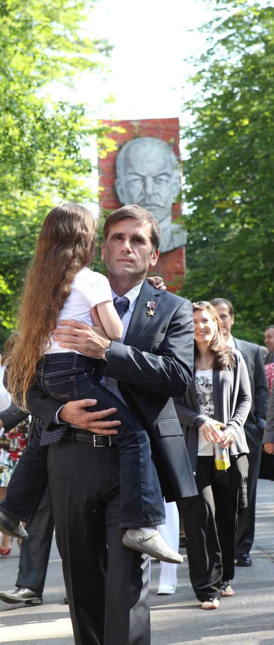 (2 July 2012) --- With the statue of Vladimir Lenin serving as a backdrop at the Gagarin Cosmonaut Training Center at Star City, Russia, Expedition 32 Soyuz Commander Yuri Malenchenko carries his daughter July 2, 2012 prior to boarding a bus that would take him and his Expedition 32 crewmates -- Japan Aerospace Exploration Agency Flight Engineer Aki Hoshide and NASA Flight Engineer Sunita Williams - to the Baikonur Cosmodrome in Kazakhstan for final preparations for their launch to the International Space Station on July 15 (Kazakhstan time) in their Soyuz TMA-05M spacecraft.   NASA/Stephanie Stoll  