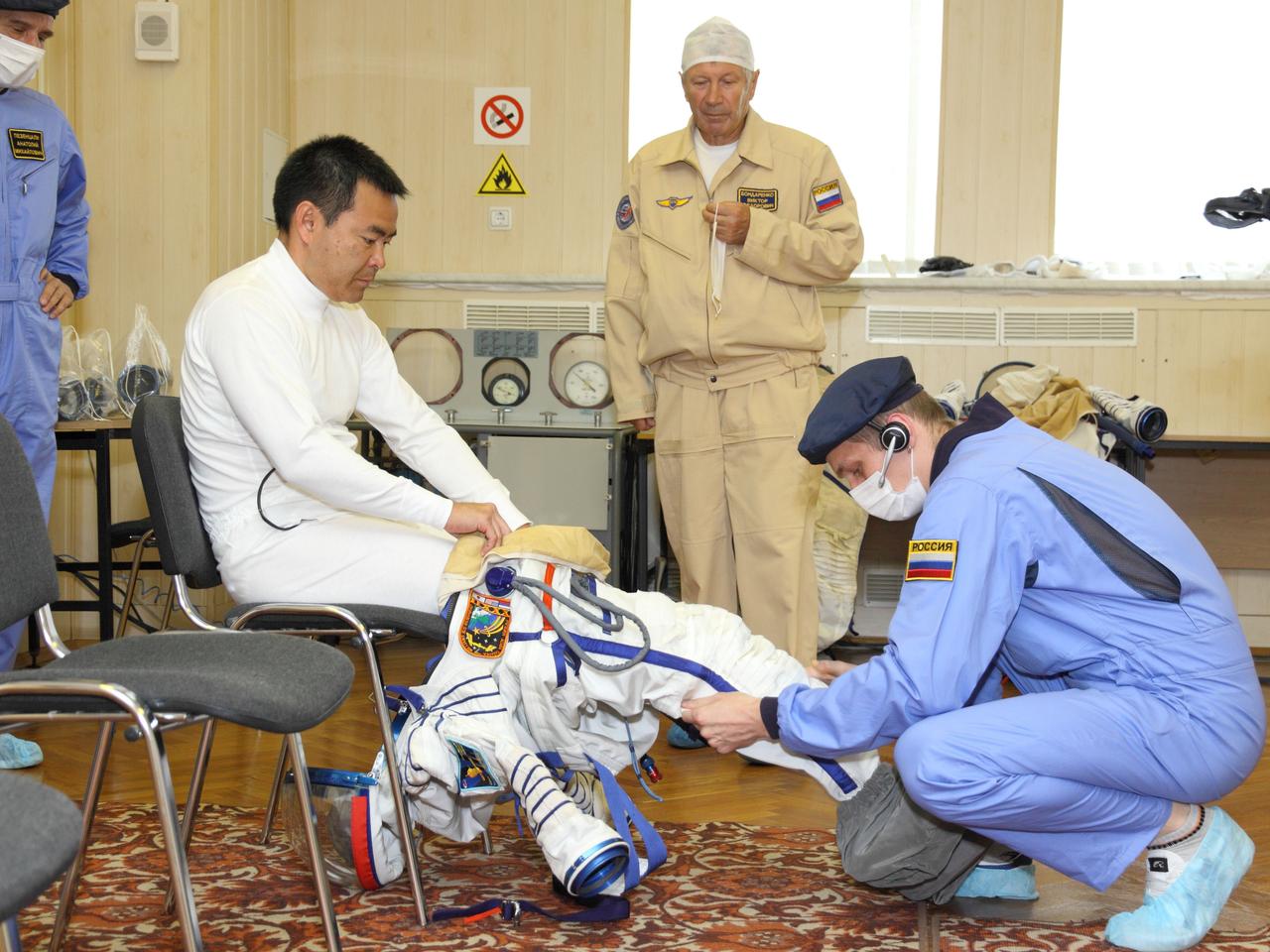 At the Baikonur Cosmodrome in Kazakhstan, Expedition 32/33 Flight Engineer Aki Hoshide of the Japan Aerospace Exploration Agency climbs into his Russian launch and entry suit July 3, 2012 for the suited “fit check” in the Soyuz TMA-05M spacecraft that will launch him, Soyuz Commander Yuri Malenchenko and NASA Flight Engineer Sunita Williams to the International Space Station on July 15.  NASA/Victor Zelentsov 