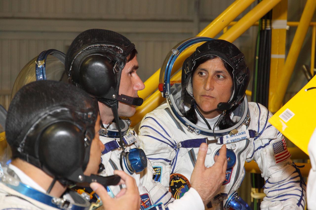 At the Baikonur Cosmodrome in Kazakhstan, Expedition 32/33 Flight Engineer Aki Hoshide of the Japan Aerospace Exploration Agency (left), Soyuz Commander Yuri Malenchenko (center) and Flight Engineer Sunita Williams of NASA (right) confer during a briefing July 3, 2012 as part of a suited “fit check” of the Soyuz TMA-05M vehicle that will launch the trio to the International Space Station on July 15.  NASA/Victor Zelentsov 
