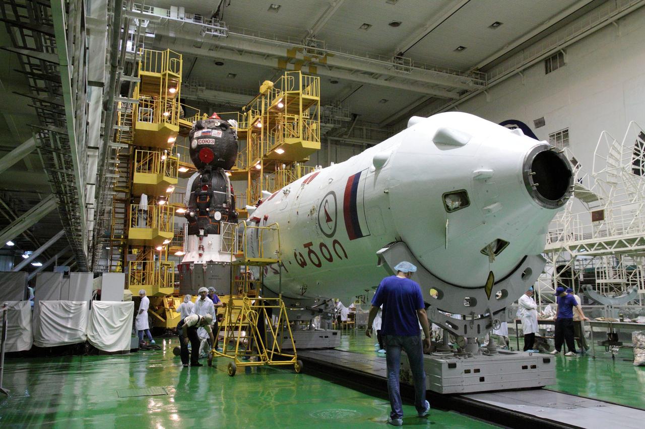 With the upper stage of the Soyuz booster in the foreground and the Soyuz TMA-05M spacecraft in the background, technicians at the Baikonur Cosmodrome in Kazakhstan prepared to encapsulate the Soyuz vehicle into its booster July 8, 2012, setting the stage for the launch of Expedition 32/33 Soyuz Commander Yuri Malenchenko, NASA Flight Engineer Sunita Williams and Flight Aki Hoshide of the Japan Exploration and Space Agency July 15 to the International Space Station for a four-month mission.  NASA/Victor Zelentsov 