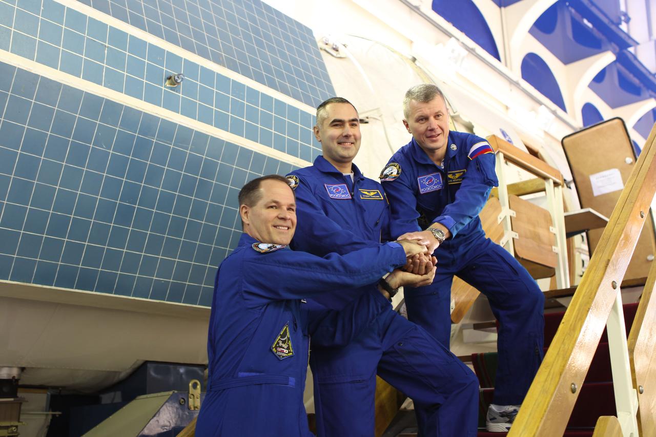 At the Gagarin Cosmonaut Training Center in Star City, Russia, Expedition 33/34 prime crewmembers Kevin Ford of NASA (left), Evgeny Tarelkin (center) and  Oleg Novitskiy (right) clasp hands as they begin the first of two days of final qualification exams September 20, 2012. Ford, Novitskiy and Tarelkin are preparing for their launch October 23 in the Soyuz TMA-06M spacecraft from the Baikonur Cosmodrome in Kazakhstan. Stephanie Stoll/NASA
