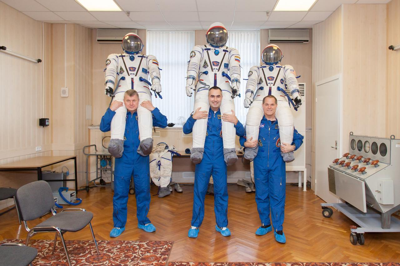 At the Baikonur Cosmodrome in Kazakhstan, the Expedition 33/34 crew shared a playful moment October 10, 2012 during the first of two so-called “fit check” dress rehearsal sessions, hoisting their Russian Sokol launch and entry suits over their heads as they prepared for launch October 23 in their Soyuz TMA-06M spacecraft to begin a five-month mission on the International Space Station. From left to right are NASA Flight Engineer Kevin Ford, Soyuz Commander Oleg Novitskiy and Flight Engineer Evgeny Tarelkin. NASA/Victor Zelentsov