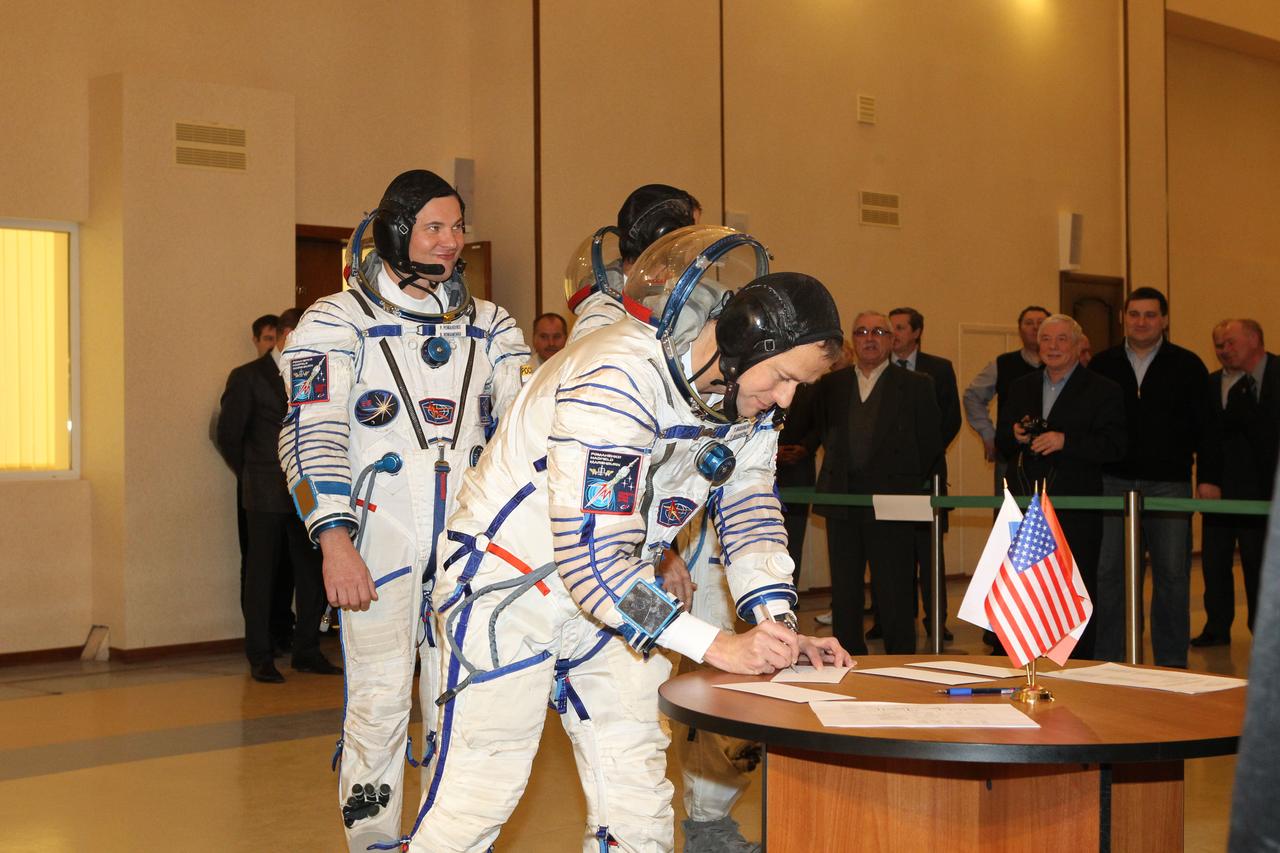 At the Gagarin Cosmonaut Training Center in Star City, Russia, Expedition 34/35 Flight Engineer Tom Marshburn of NASA signs in for the second of two days of flight qualification exams Nov. 28, 2012. He and his crewmates are preparing for launch Dec. 19 to the International Space Station from the Baikonur Cosmodrome in Kazakhstan aboard the Soyuz TMA-07M spacecraft. Looking on behind Marshburn are Soyuz Commander Roman Romanenko (left) and Flight Engineer Chris Hadfield of the Canadian Space Agency (partially hidden). NASA/Stephanie Stoll
