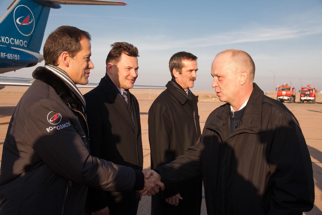 In Baikonur, Kazakhstan, Expedition 34/35 Flight Engineer Tom Marshburn of NASA (far left) ) is greeted by a Russian space official as he, Soyuz Commander Roman Romanenko (second from left) and Flight Engineer Chris Hadfield of the Canadian Space Agency (third from left) arrived from Star City, Russia Dec. 6, 2012 to begin final training for their launch Dec. 19 from the Baikonur Cosmodrome on the Soyuz TMA-07M spacecraft for a five-month mission on the International Space Station. Photo Credit: NASA/Victor Zelentsov