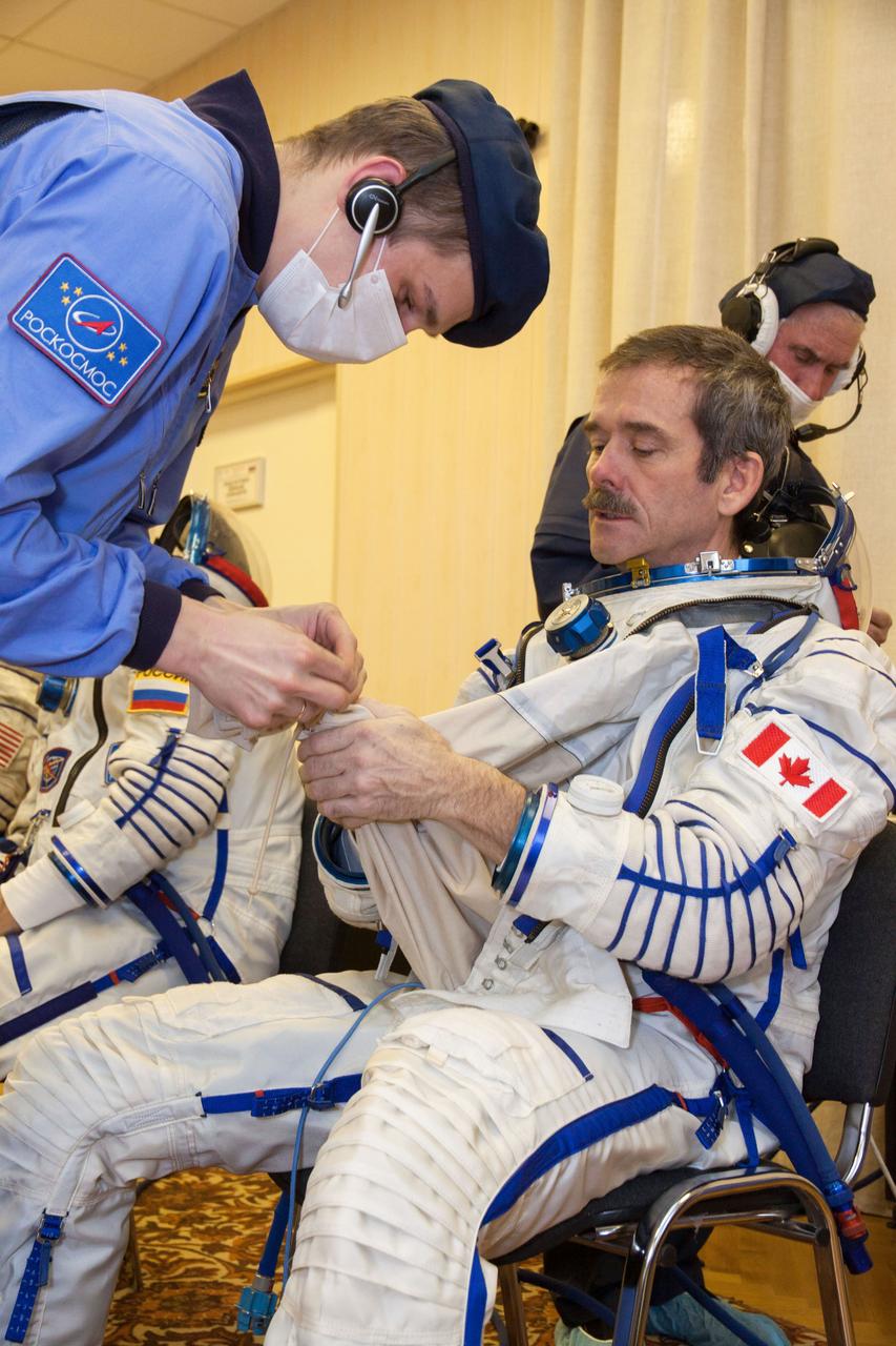 At the Baikonur Cosmodrome in Kazakhstan, Expedition 34/35 Flight Engineer Chris Hadfield of the Canadian Space Agency suits up in his Russian Sokol launch and entry suit Dec. 7, 2012 during a “fit check” dress rehearsal for launch in the Soyuz TMA-07M spacecraft. Hadfield, Soyuz Commander Roman Romanenko and Flight Engineer Tom Marshburn of NASA will launch Dec. 19 for a five-month mission on the International Space Station. Photo Credit: NASA/Victor Zelentsov