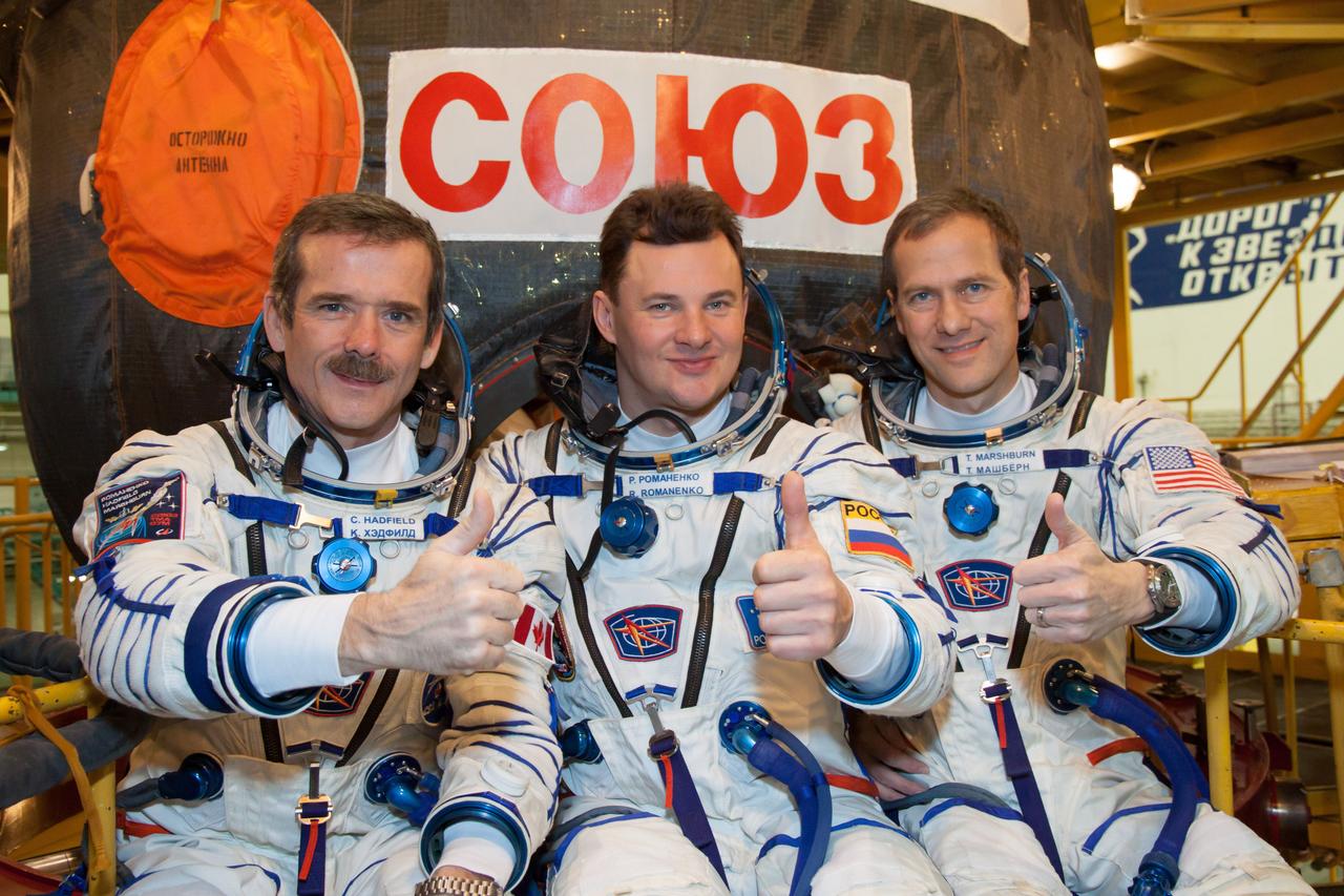 At the Baikonur Cosmodrome in Kazakhstan, Expedition 34/35 Flight Engineer Chris Hadfield of the Canadian Space Agency (left), Soyuz Commander Roman Romanenko (center) and Flight Engineer Tom Marshburn of NASA (right) flash a thumbs up Dec. 7, 2012 in front of their Soyuz TMA-07M spacecraft after a “fit check” dress rehearsal. They are preparing for launch Dec. 19 for five-month mission on the International Space Station. Photo Credit: NASA/Victor Zelentsov