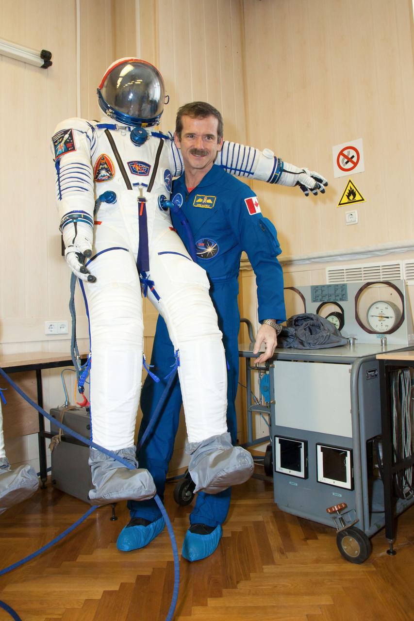 At the Baikonur Cosmodrome in Kazakhstan, Expedition 34/35 Flight Engineer Chris Hadfield of the Canadian Space Agency strikes a playful pose with his Sokol launch and entry suit Dec. 7, 2012 during a “fit check” dress rehearsal. Hadfield, Soyuz Commander Roman Romanenko and Flight Engineer Tom Marshburn of NASA are preparing for launch Dec. 19 in their Soyuz TMA-07M spacecraft for a five-month mission on the International Space Station. Photo Credit: NASA/Victor Zelentsov