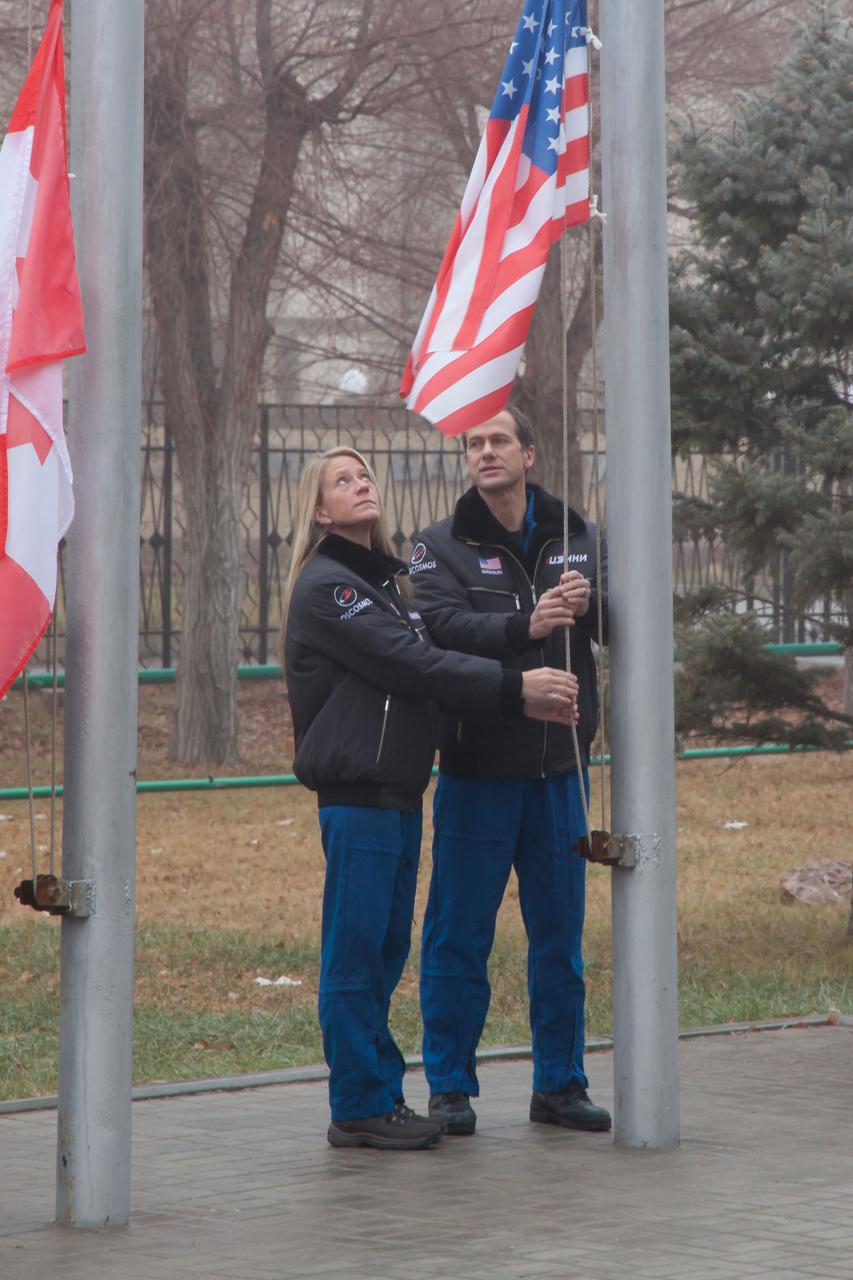 Expedition 34/35 Flight Engineer Tom Marshburn of NASA (right) is assisted by his backup, Flight Engineer Karen Nyberg (left) as they raise the U.S. flag outside their Cosmonaut Hotel crew quarters in Baikonur, Kazakhstan Dec. 9, 2012. The flag-raising ceremony was part of the pre-launch activities that will lead to the launch of Marshburn, Soyuz Commander Roman Romanenko and Flight Engineer Chris Hadfield of the Canadian Space Agency Dec. 19 from the Baikonur Cosmodrome in their Soyuz TMA-07M spacecraft for a five-month mission on the International Space Station. Photo Credit: NASA/Victor Zelentsov