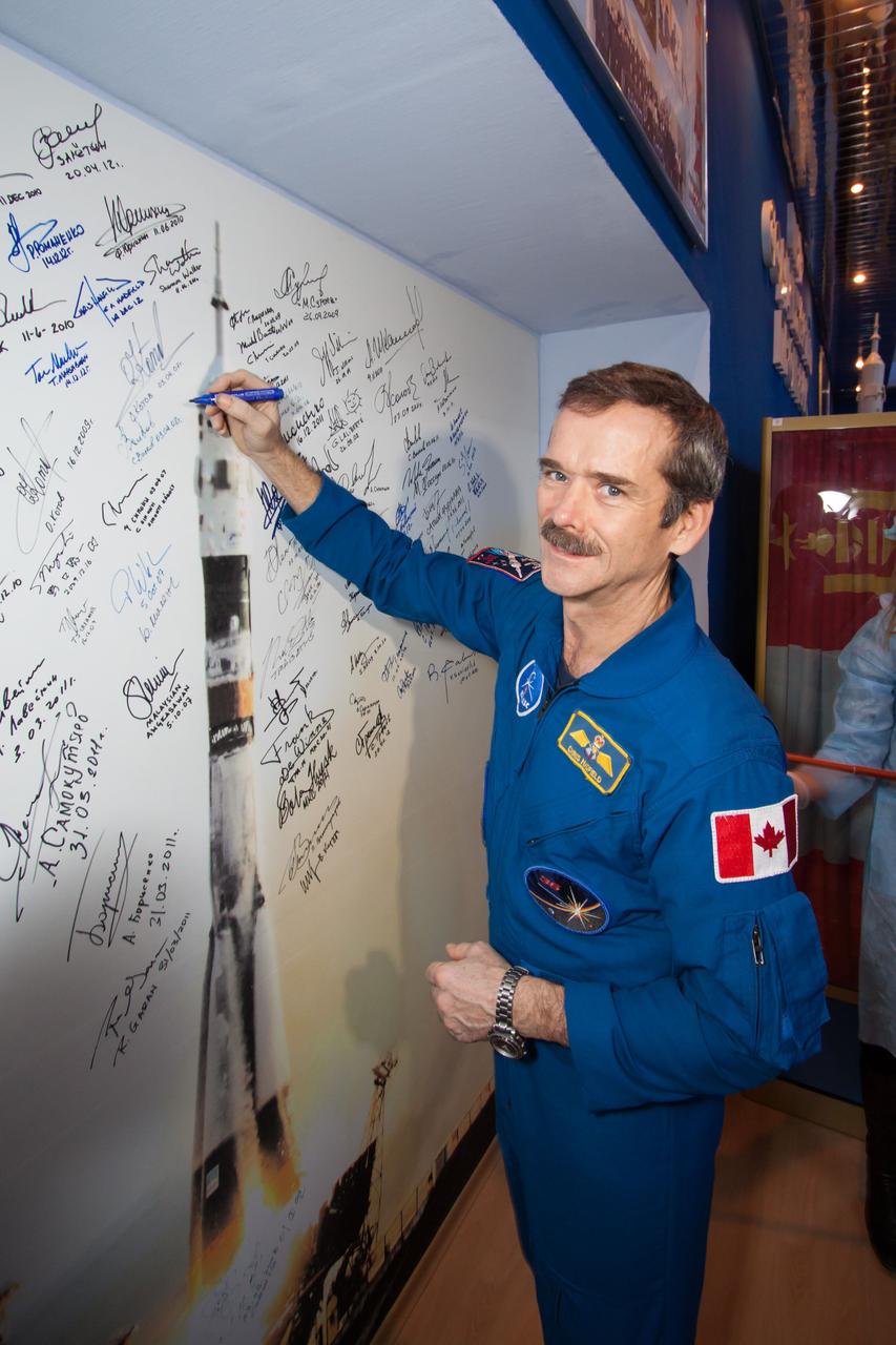 At the Korolev Museum at the Baikonur Cosmodrome in Kazakhstan, Expedition 34/35 Flight Engineer Chris Hadfield of the Canadian Space Agency signs a mural of a Soyuz spacecraft launch Dec. 14, 2012, part of a tradition for all space travelers launching from the Central Asian spaceport. Hadfield, Soyuz Commander Roman Romanenko and Flight Engineer Tom Marshburn of NASA will launch Dec. 19 in the Soyuz TMA-07M spacecraft from Baikonur for a five-month mission on the International Space Station. NASA/Victor Zelentsov