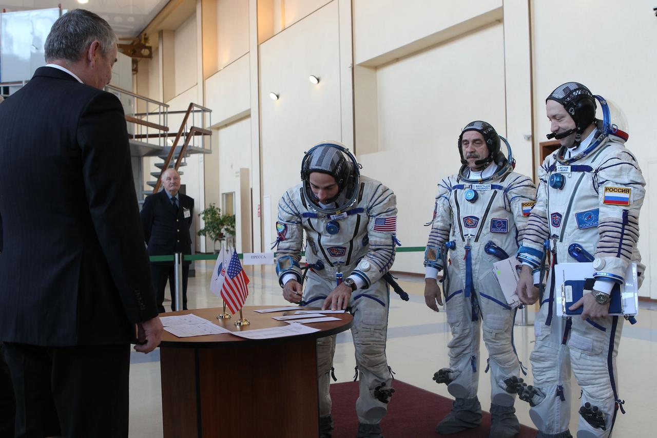 At the Gagarin Cosmonaut Training Center in Star City, Russia, Expedition 35-36 Flight Engineer Chris Cassidy of NASA (second from left) signs a book before Russian space officials March 5, certifying that he is prepared to begin qualification simulation runs in a Soyuz spacecraft mockup. Looking on are Soyuz Commander Pavel Vinogradov (second from right) and Flight Engineer Alexander Misurkin (right). The three crewmembers are training for launch March 29, Kazakh time, to the International Space Station in their Soyuz TMA-08M spacecraft from the Baikonur Cosmodrome in Kazakhstan. NASA / Stephanie Stoll