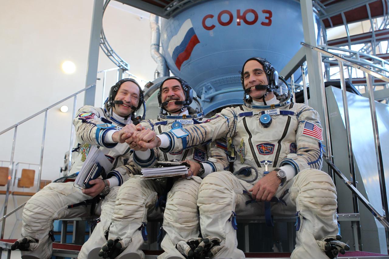 At the Gagarin Cosmonaut Training Center in Star City, Russia, Expedition 35-36 Flight Engineer Chris Cassidy (right), Soyuz Commander Pavel Vinogradov (center) and Flight Engineer Alexander Misurkin (left) clasp hands for photographers prior to the start of qualification simulation runs in a Soyuz spacecraft mockup March 5. The three crewmembers are training for launch March 29, Kazakh time, to the International Space Station in their Soyuz TMA-08M spacecraft from the Baikonur Cosmodrome in Kazakhstan. NASA / Stephanie Stoll