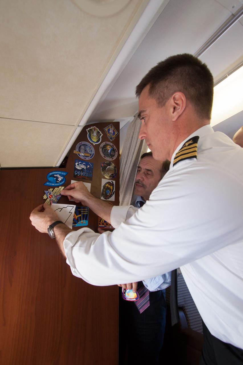 Aboard a Russian Federal Space Agency aircraft carrying him and his crewmates to their launch site, Expedition 35-36 Flight Engineer Chris Cassidy of NASA affixes a sticker of his crew insignia to the wall of the cabin of the plane March 16 as crewmate Pavel Vinogradov looks on. Cassidy, Vinogradov and Flight Engineer Alexander Misurkin flew from their training base in Star City, Russia to the Baikonur, Kazakhstan for final training for their launch to the International Space Station on March 29, Kazakh time, in their Soyuz TMA-08M spacecraft from the Baikonur Cosmodrome. NASA/Victor Zelentsov