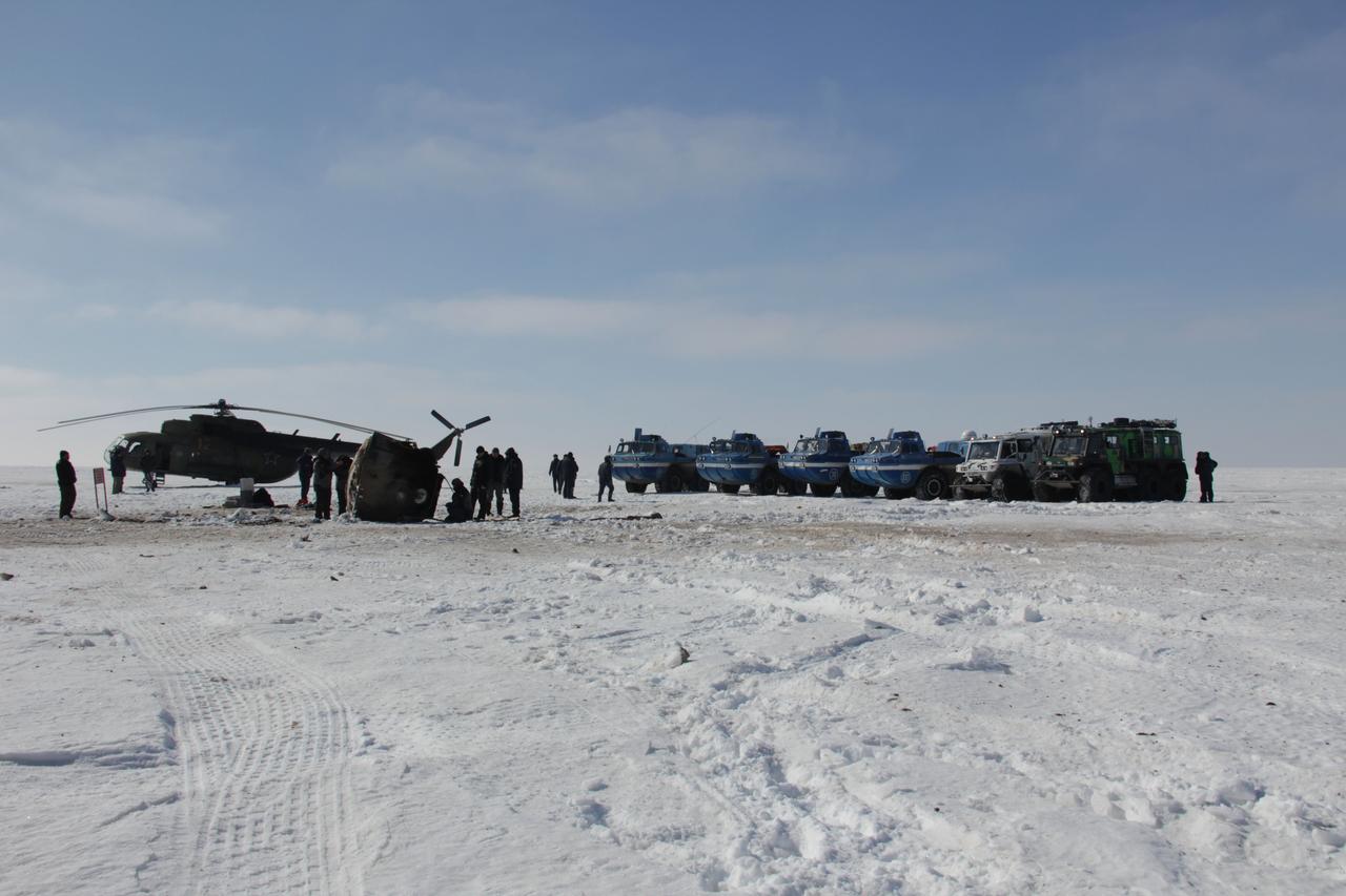 Russian “Rosaviatsa” Search and Recovery Forces all-terrain vehicles and a helicopter stand beside the Soyuz TMA-06M spacecraft March 16 just hours after Expedition 34 Commander Kevin Ford of NASA, Soyuz Commander Oleg Novitskiy and Flight Engineer Evgeny Tarelkin safely landed northeast of Arkalyk, Kazakhstan following a one-day delay due to inclement weather in the area. The three crewmembers were quickly extracted from the Soyuz after landing and were flown in helicopters to Kustanai, Kazakhstan en route to their respective homes in Houston and Star City, Russia following 144 days in space and 142 days aboard the International Space Station.  Courtesy of Sergey Vigovskiy 