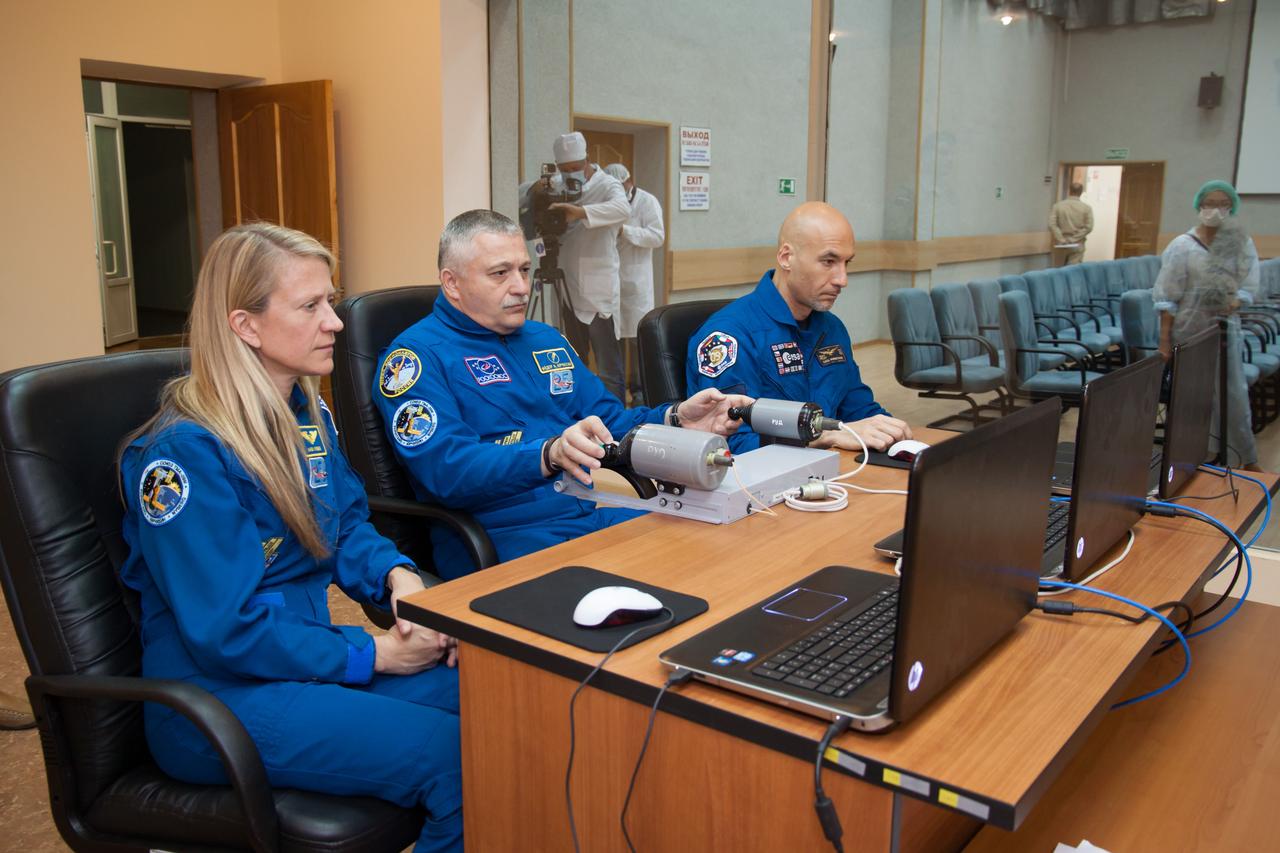 In the Cosmonaut Hotel crew quarters in Baikonur, Kazakhstan, Expedition 36/37 Soyuz Commander Fyodor Yurchikhin (center) practices a Soyuz docking on a laptop simulator May 22 as he, NASA Flight Engineer Karen Nyberg (left) and Flight Engineer Luca Parmitano of the European Space Agency (right) prepare for their launch May 29, Kazakh time, in the Soyuz TMA-09M spacecraft to begin a 5 ½ month mission on the International Space Station.  NASA/Victor Zelentsov 