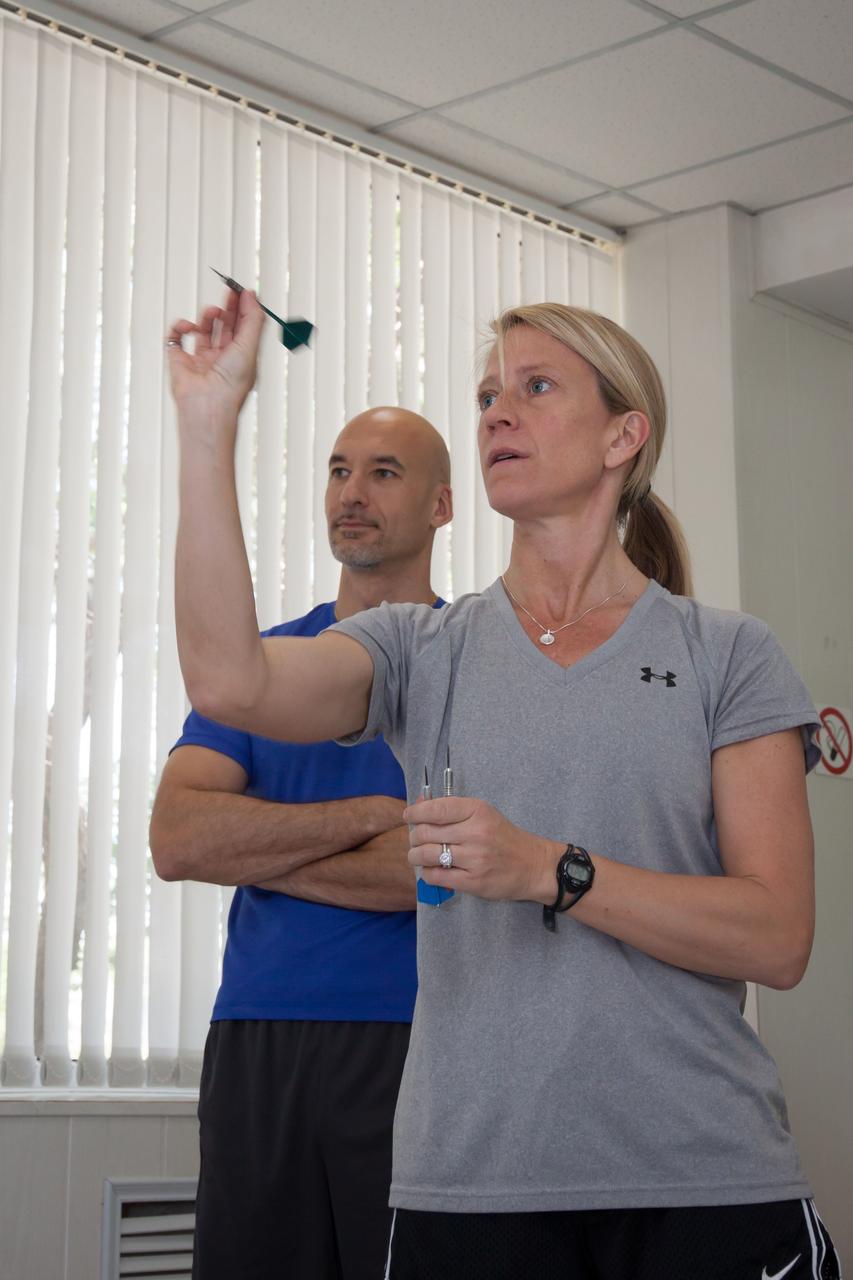 In the Cosmonaut Hotel crew quarters in Baikonur, Kazakhstan, Expedition 36/37 Flight Engineer Karen Nyberg of NASA takes a turn at a game of darts May 22 as Flight Engineer Luca Parmitano of the European Space Agency (background) looks on. Nyberg, Parmitano and Soyuz Commander Fyodor Yurchikhin are preparing for launch May 29, Kazakh time, in the Soyuz TMA-09M spacecraft to begin a 5 ½ month mission on the International Space Station.  NASA/Victor Zelentsov 