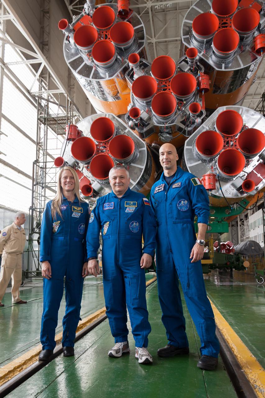 At the Baikonur Cosmodrome in Kazakhstan, Expedition 36/37 Flight Engineer Karen Nyberg of NASA (left), Soyuz Commander Fyodor Yurchikhin (center) and Flight Engineer Luca Parmitano of the European Space Agency (right) pose for pictures May 24 in front of the first stage engines of their Soyuz rocket in the Integration Facility following the final “fit check” dress rehearsal by the prime and backup crews. Nyberg, Yurchikhin and Parmitano are preparing for launch May 29, Kazakh time, in the Soyuz TMA-09M spacecraft to begin a 5 ½ month mission on the International Space Station. NASA/Victor Zelentsov
