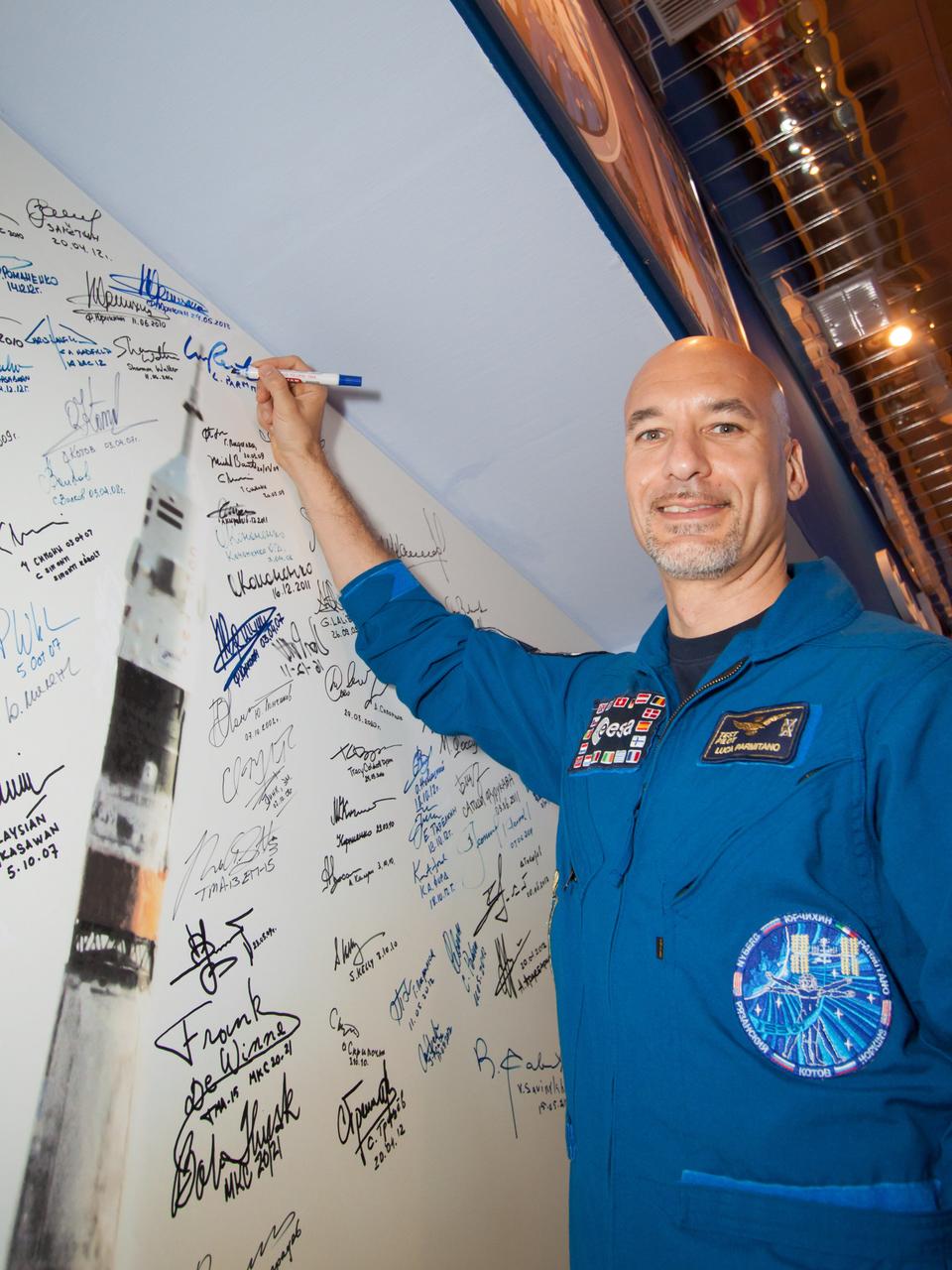 At the Baikonur Cosmodrome in Kazakhstan, Expedition 36/37 Flight Engineer Luca Parmitano of the European Space Agency signs a mural depicting a Soyuz rocket launch in the Korolev Museum May 24 following the final “fit check” dress rehearsal before launch. Parmitano, NASA Flight Engineer Karen Nyberg and Soyuz Commander Fyodor Yurchikhin are preparing for launch May 29, Kazakh time, in the Soyuz TMA-09M spacecraft to begin a 5 ½ month mission on the International Space Station.  NASA/Victor Zelentsov 