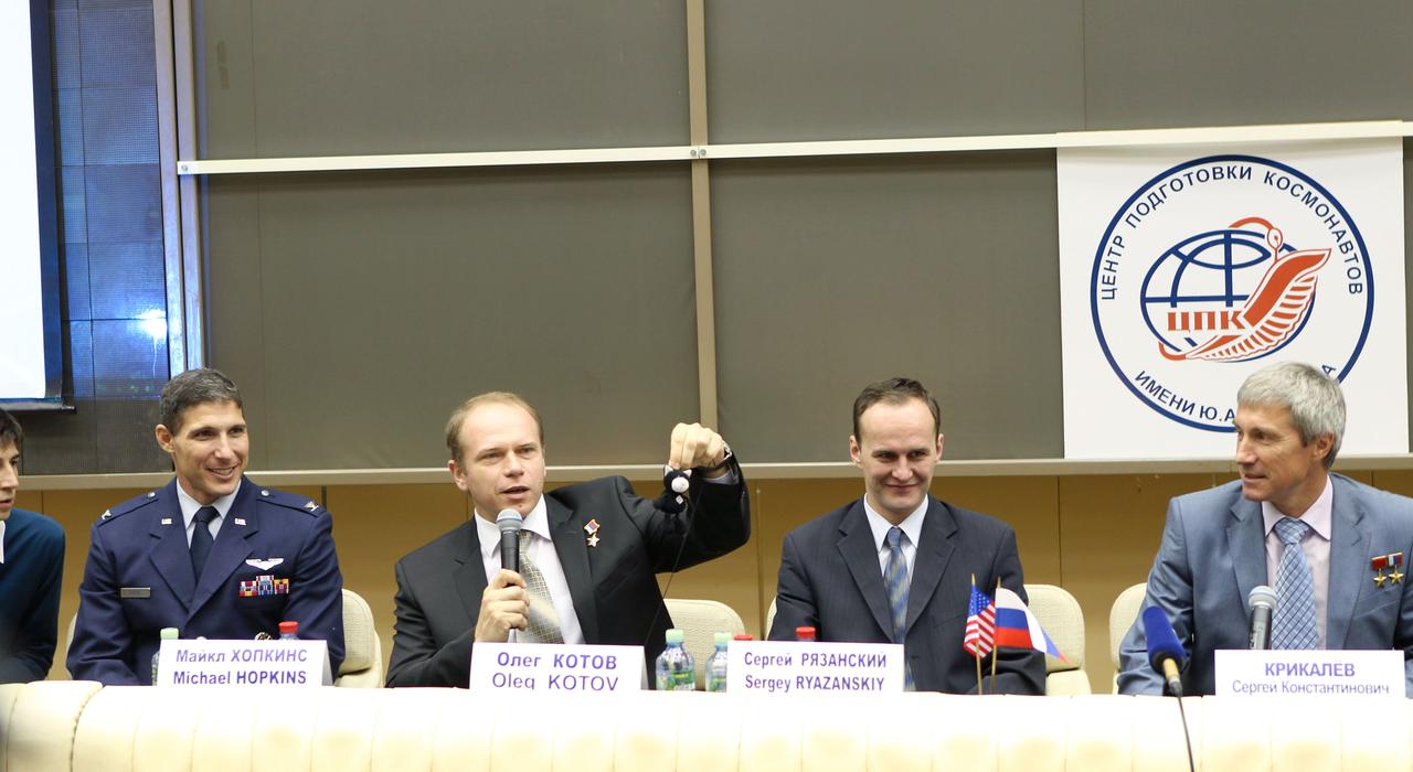 At the Gagarin Cosmonaut Training Center in Star City, Russia, Expedition 37/38 Soyuz Commander Oleg Kotov (second from left) holds a toy cat mascot during a pre-launch news conference Sept. 6 as his crewmates, Flight Engineer Michael Hopkins of NASA (far left) and Flight Engineer Sergey Ryazanskiy (second from the right) look on. Also participating in the news conference was the head of the Cosmonaut Training Center, Sergei Krikalev (far right). The mascot will be mounted inside the crew’s Soyuz TMA-10M spacecraft over Kotov’s head as a “zero-g indicator” once the crew launches. Their launch to the International Space Station is set for Sept. 26, Kazakh time, from the Baikonur Cosmodrome in Kazakhstan.  NASA/Stephanie Stoll
