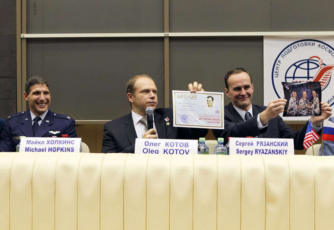 At the Gagarin Cosmonaut Training Center in Star City, Russia, Expedition 37/38 Soyuz Commander Oleg Kotov (center) holds up a certificate proclaiming his readiness to launch and his crewmate, Flight Engineer Sergey Ryazanskiy (right) holds up a crew portrait Sept. 6 as NASA Flight Engineer Michael Hopkins (left) looks on. Hopkins, Kotov and Ryazanskiy are preparing for their launch to the International Space Station from the Baikonur Cosmodrome in Kazakhstan on Sept. 26, Kazakh time, aboard the Soyuz TMA-10M spacecraft.  NASA/Stephanie Stoll