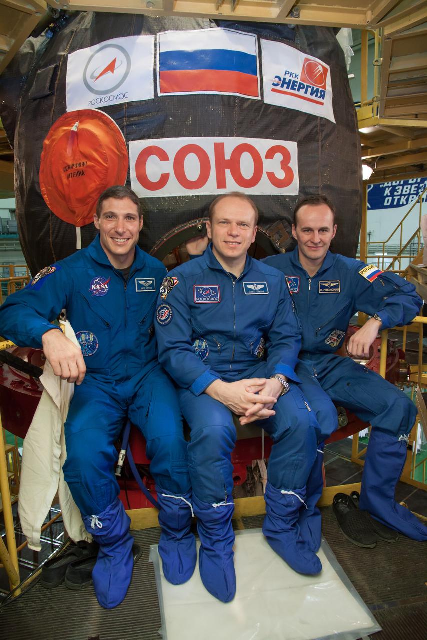 At the Baikonur Cosmodrome in Kazakhstan, Expedition 37/38 Flight Engineer Michael Hopkins of NASA (left), Soyuz Commander Oleg Kotov (center) and Flight Engineer Sergey Ryazanskiy (right) pose for pictures in front of their Soyuz TMA-10M spacecraft Sept. 14 during a “fit check” dress rehearsal training exercise. The three crewmembers are preparing for launch Sept. 26, Kazakh time, from Baikonur to begin a five and a half month mission on the International Space Station.  NASA/Victor Zelentsov 