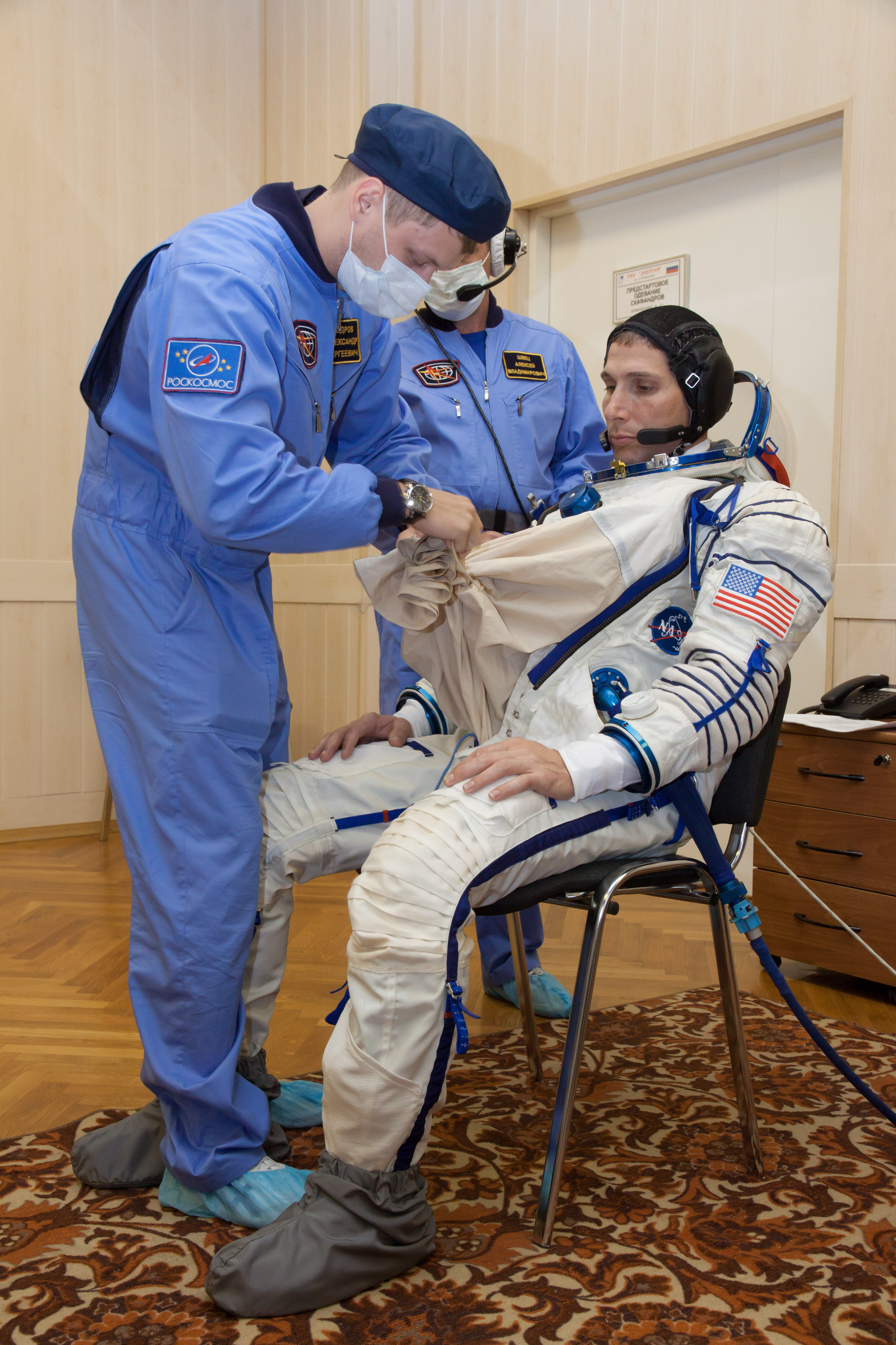 At the Baikonur Cosmodrome in Kazakhstan, Expedition 37/38 Flight Engineer Michael Hopkins of NASA is helped into his Russian Sokol launch and entry suit Sept. 14 for a “fit check” dress rehearsal training exercise. Hopkins, Soyuz Commander Oleg Kotov and Flight Sergey Ryazanskiy are preparing for launch Sept. 26, Kazakh time, from Baikonur on their Soyuz TMA-10M spacecraft to begin a five and a half month mission on the International Space Station.  NASA/Victor Zelentsov 