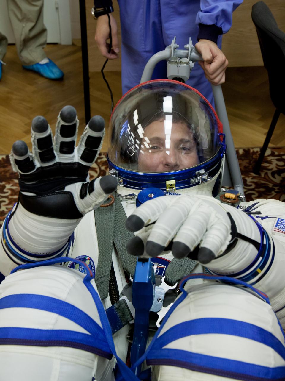 At the Baikonur Cosmodrome in Kazakhstan, Expedition 37/38 Flight Engineer Michael Hopkins of NASA waves during a pressure check of his Russian Sokol launch and entry suit Sept. 14 as part of a “fit check” dress rehearsal training exercise. Hopkins, Soyuz Commander Oleg Kotov and Flight Sergey Ryazanskiy are preparing for launch Sept. 26, Kazakh time, from Baikonur on their Soyuz TMA-10M spacecraft to begin a five and a half month mission on the International Space Station.  NASA/Victor Zelentsov 